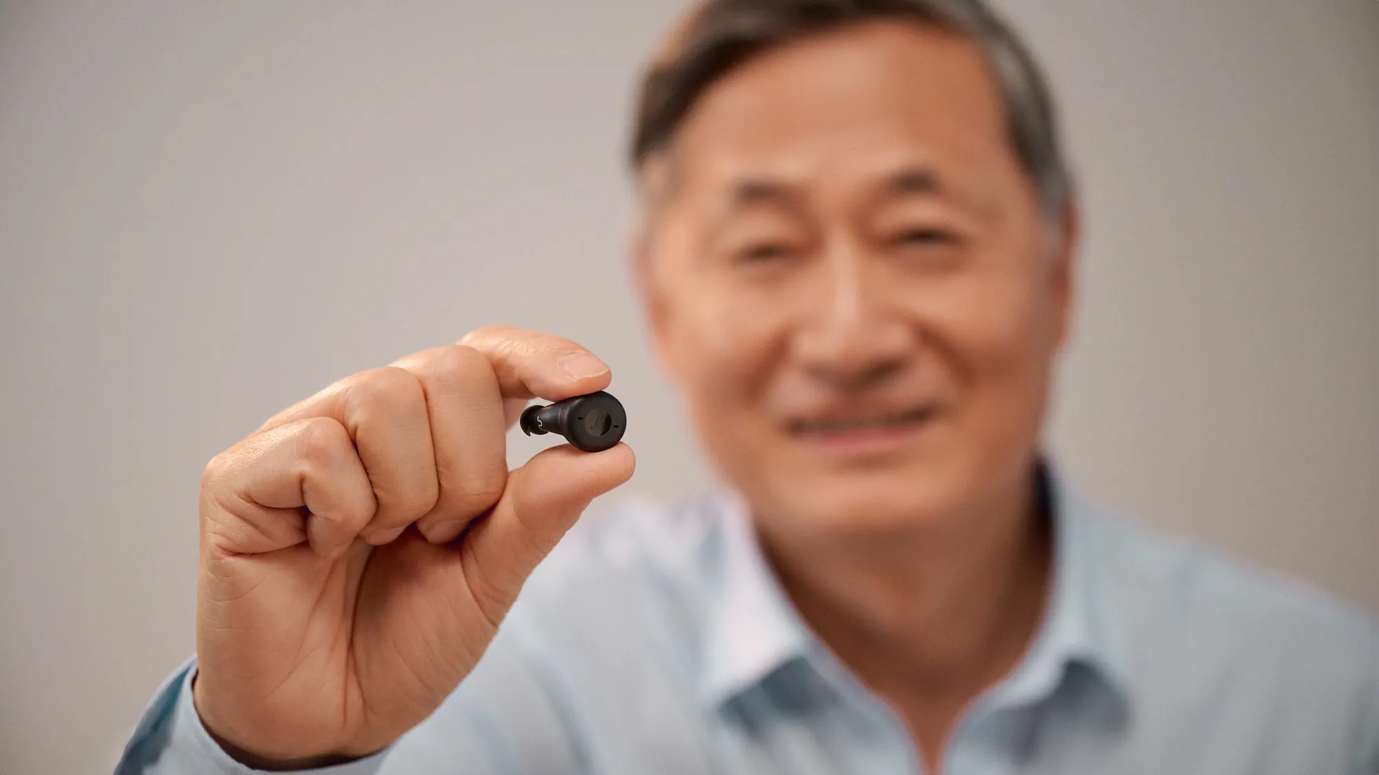 Man holding Signia Active between his fingers to show how tiny it is