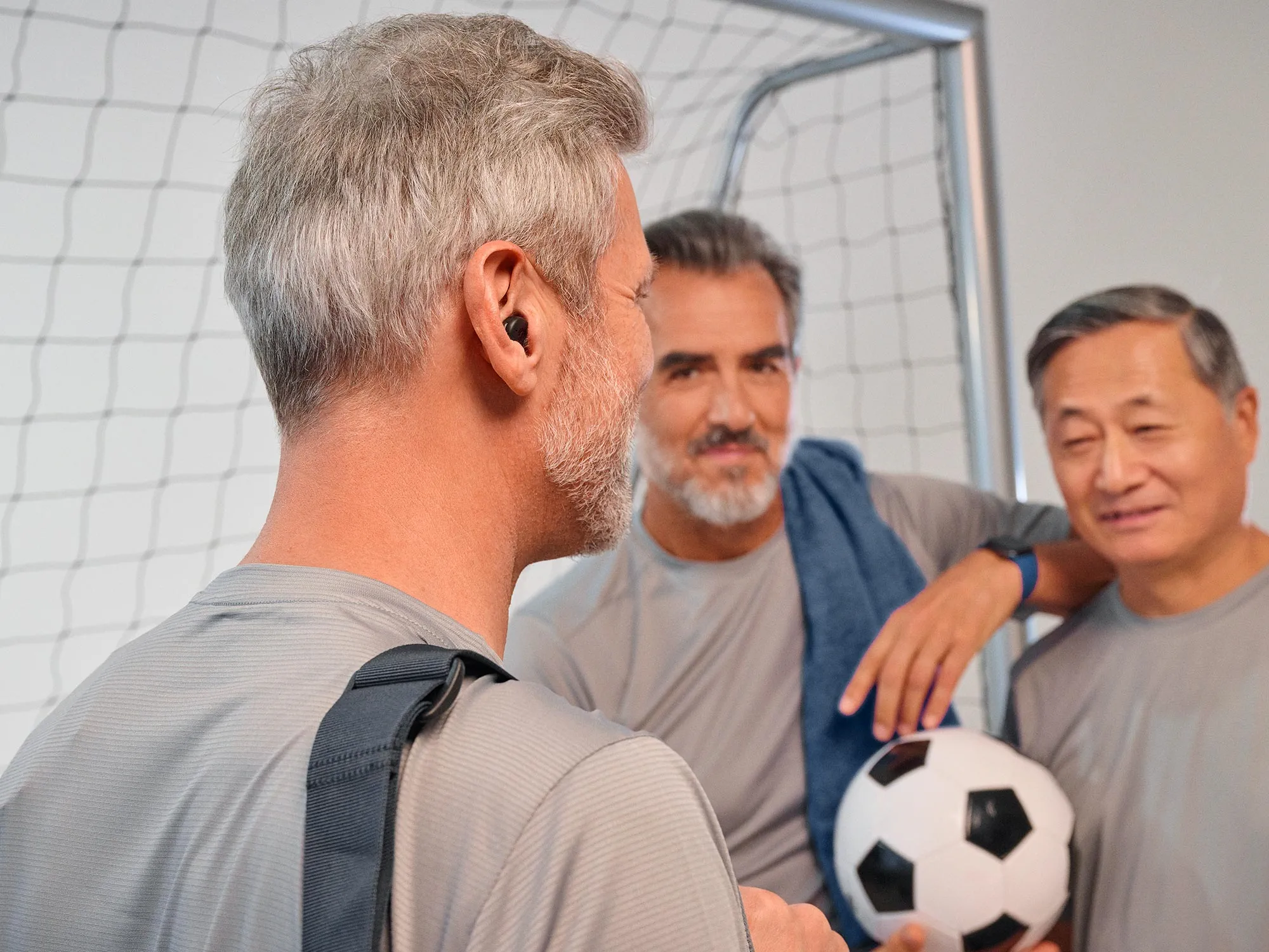 Mann spielt Fußball und trägt Signia Active Hörgeräte.
