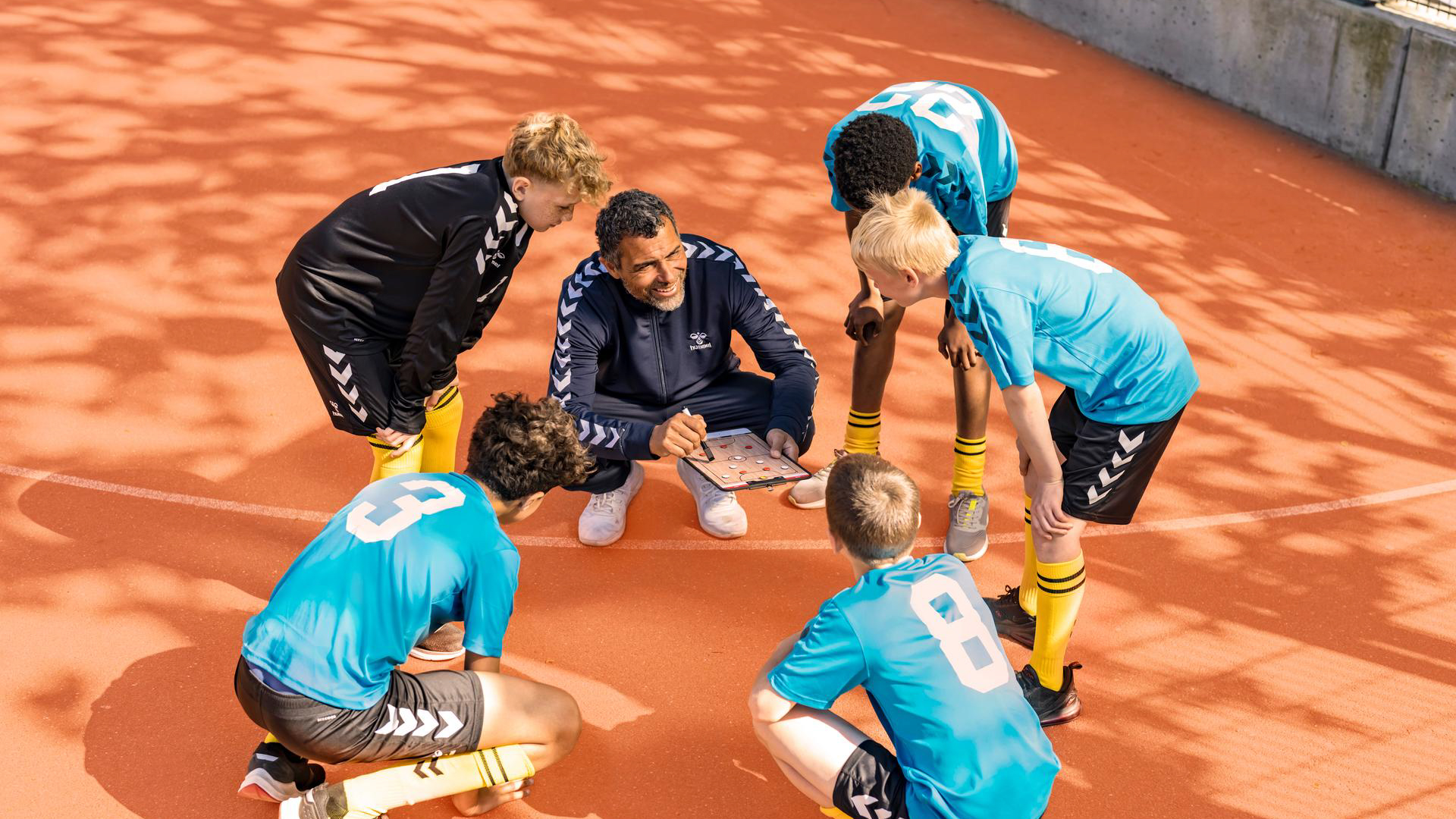Signia IX-Trainer bespricht Taktiken mit seinem Team, das Hörgeräte trägt.