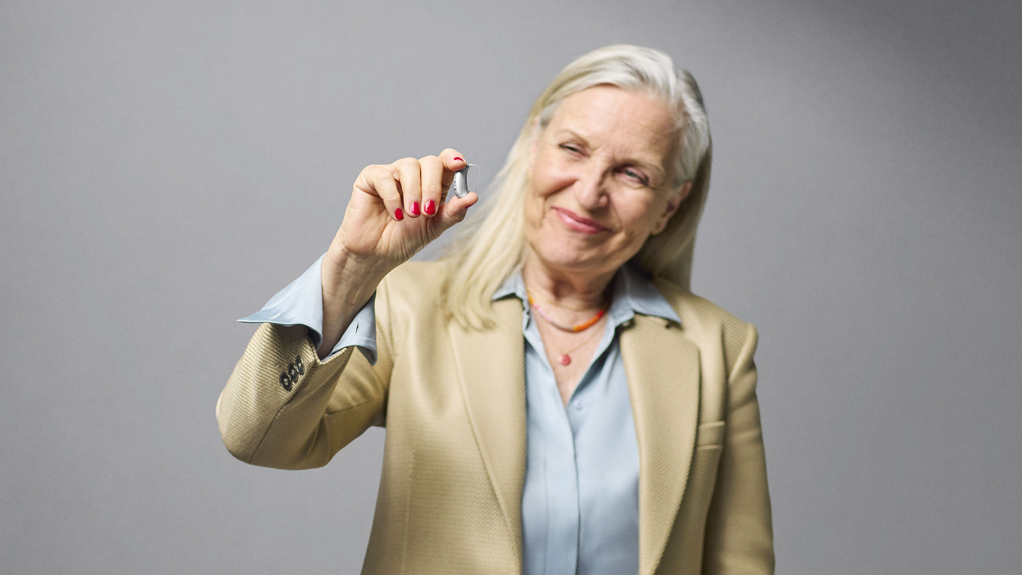 Signia Motion Charge&Go IX hearing aid pinched between fingers for size comparison