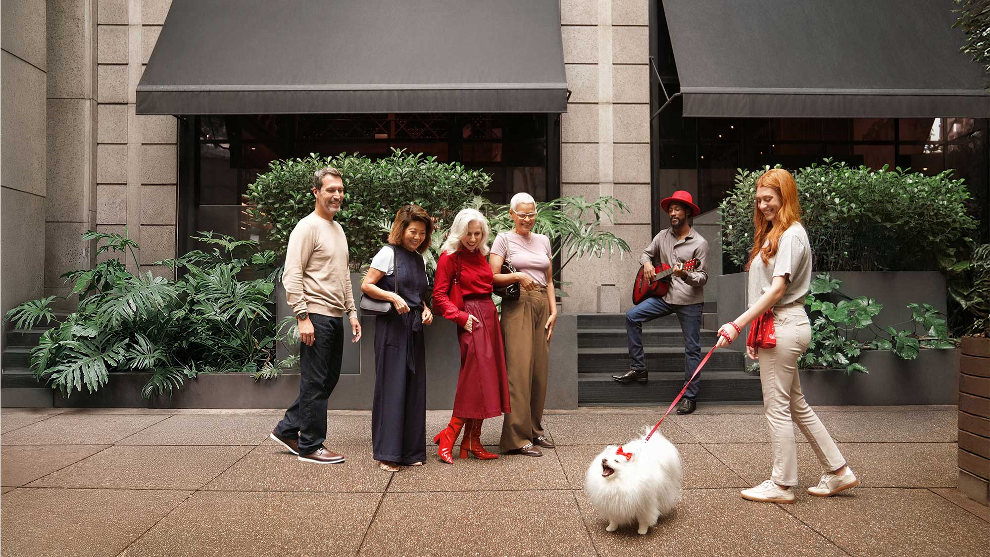 A woman with friends and a dog in the city wearing Signia hearing aids, blending style with hearing-loss support.
