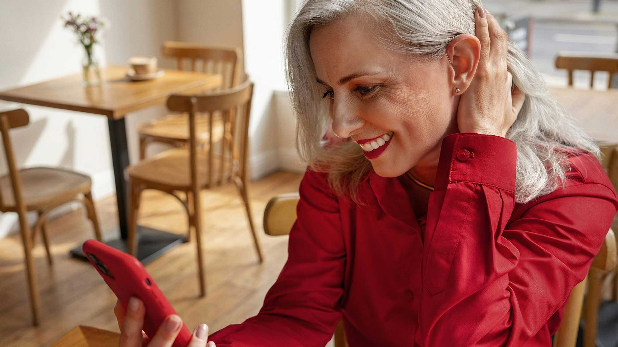A woman wearing Signia Pure Charge&Go Max hearing aids while talking on the phone, emphasizing connectivity and hearing-loss support.