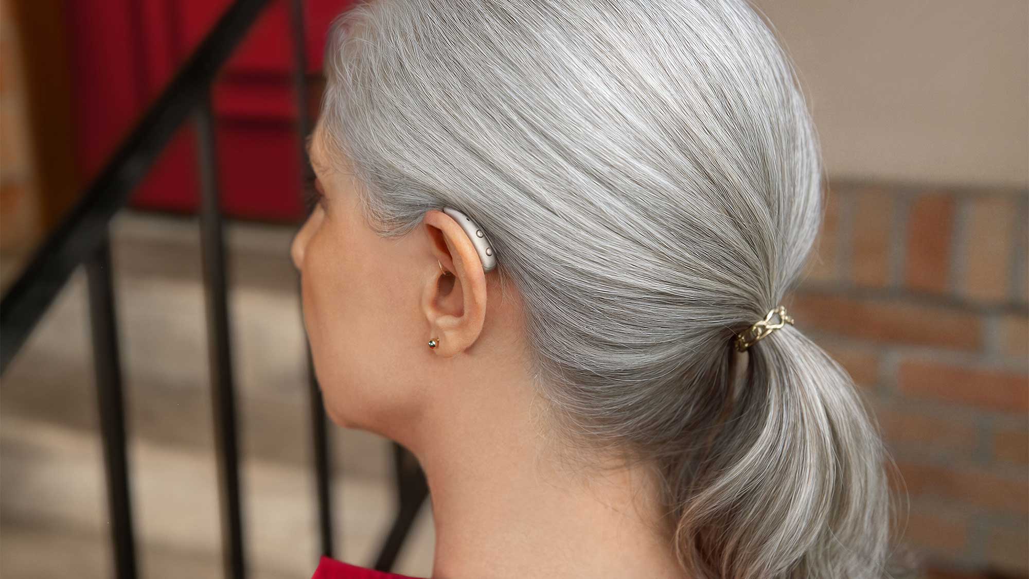 Side view of a woman wearing Signia Pure Charge&Go Max hearing aids, showcasing discreet design and hearing-loss support.