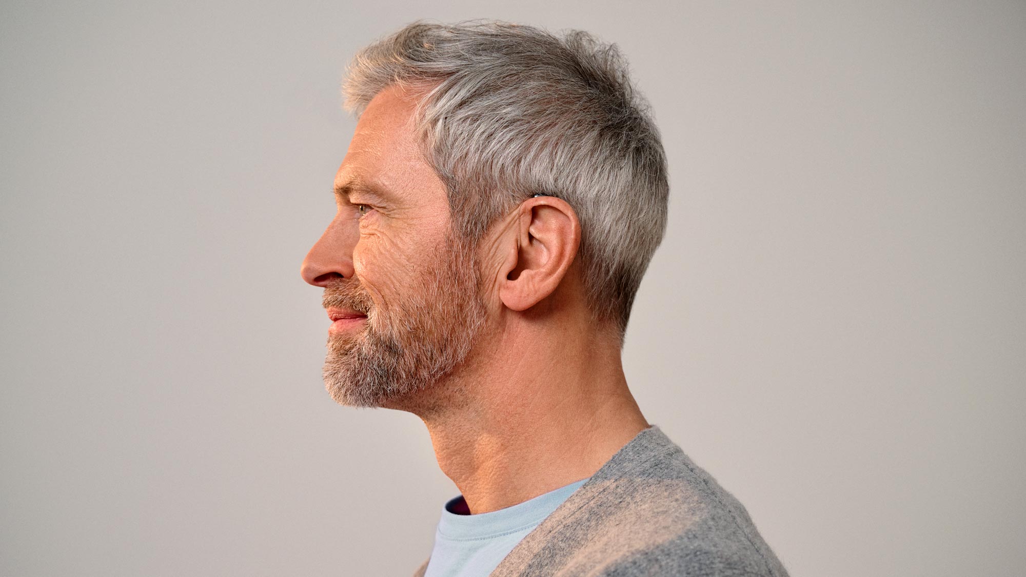 Man seen from the side wearing Signia Pure hearing aids. See how small they are.