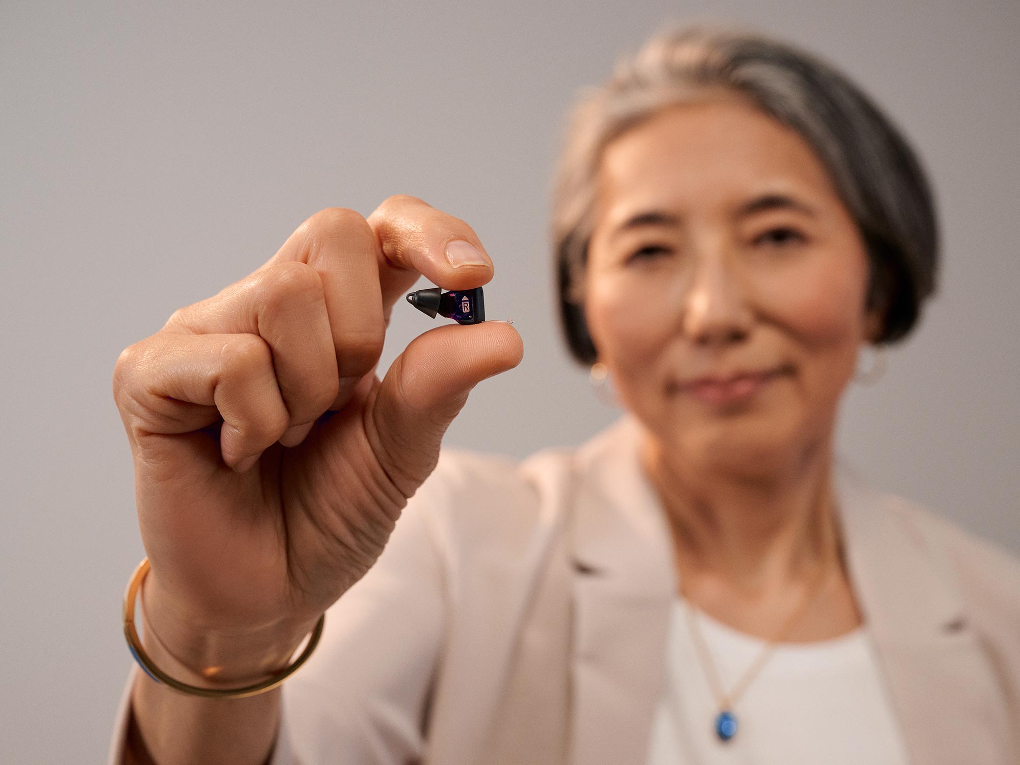 Woman holding Signia Silk between her fingers to show how tiny it is