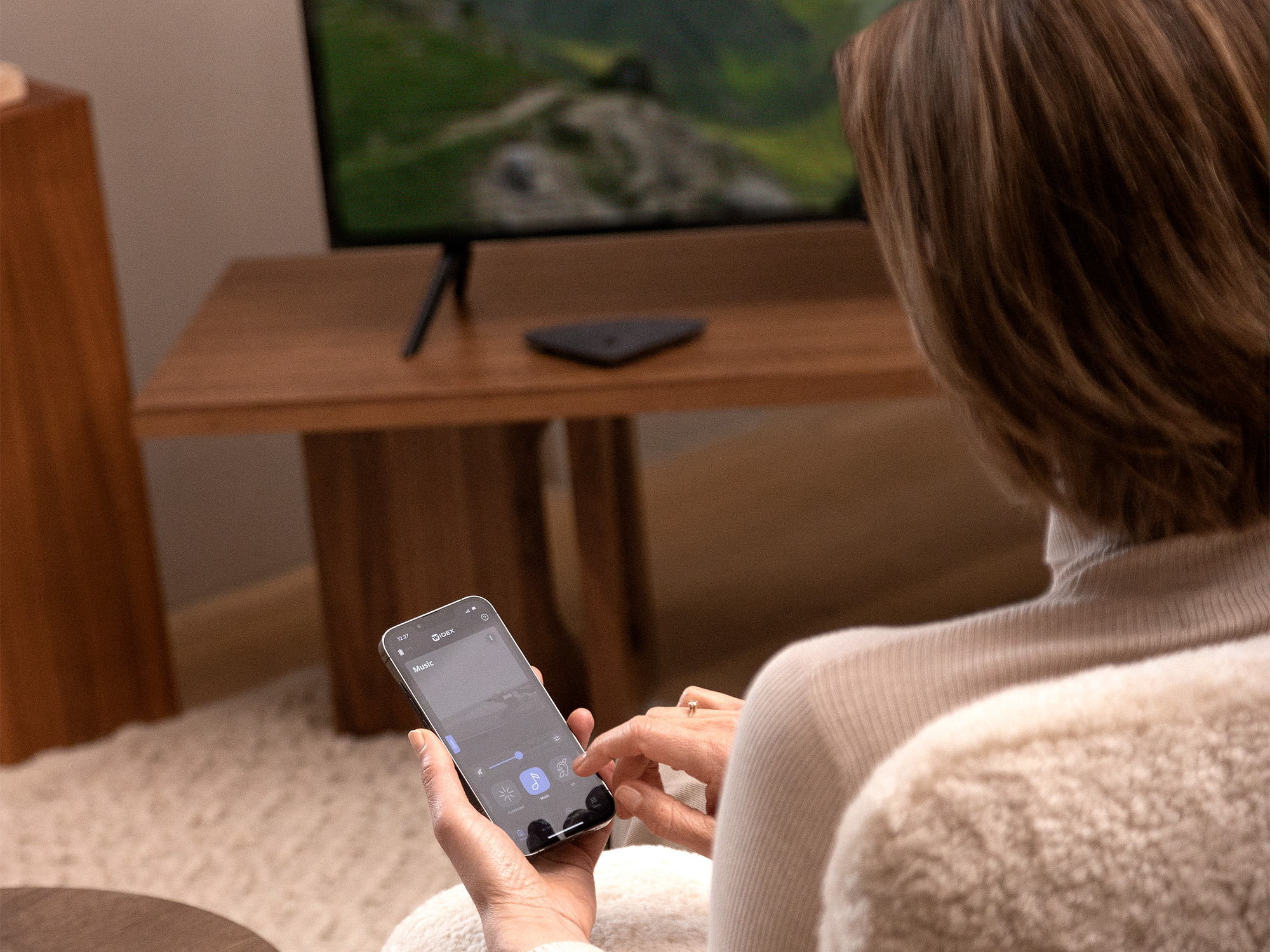 Frau trägt Widex Moment Sheer Hörgeräte und verbindet sich mit Widex TV Play, um den Ton direkt auf ihre Hörgeräte zu übertragen.