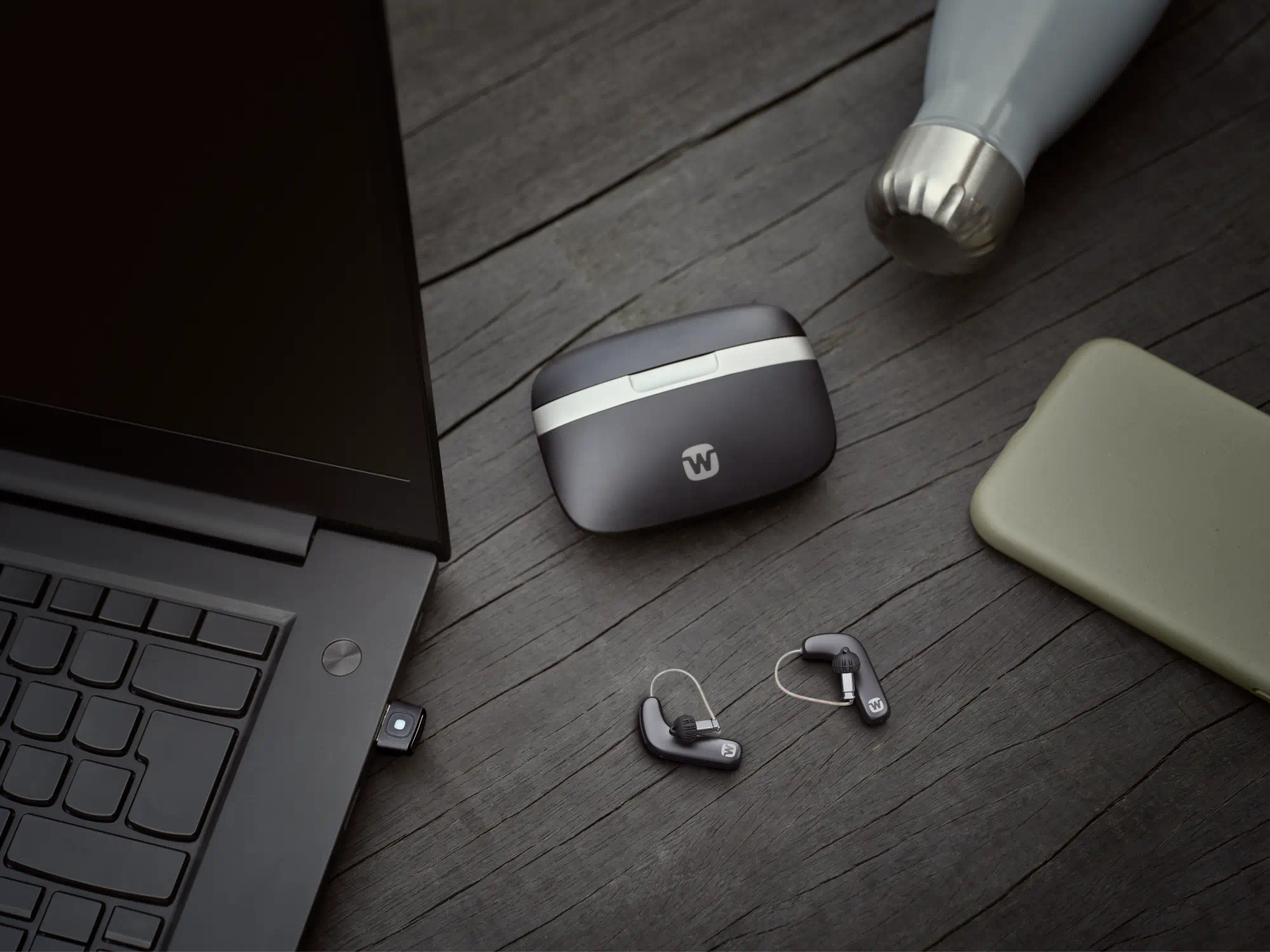 Widex Allure hearing aids shown next to glass to illustrate how small they are.