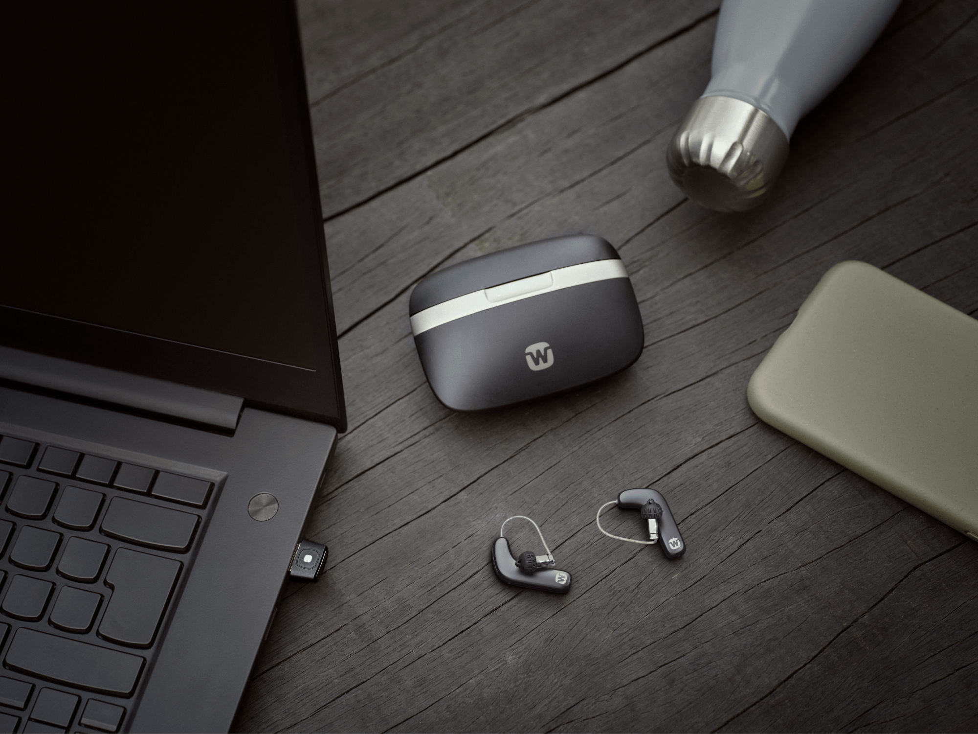 Widex Allure hearing aids shown next to glass to illustrate how small they are.