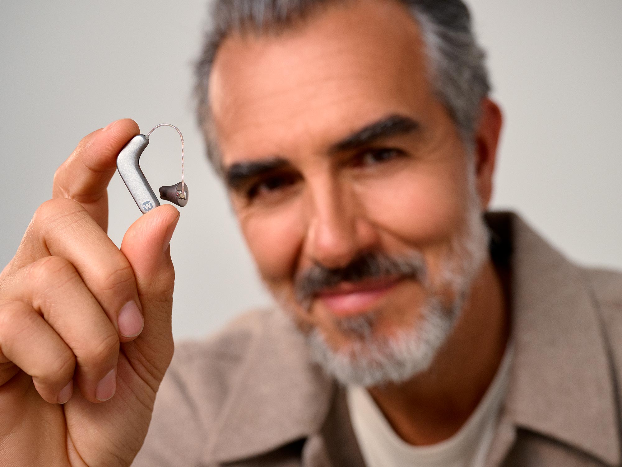 Man holding Widex SmartRIC between his fingers to show how tiny it is