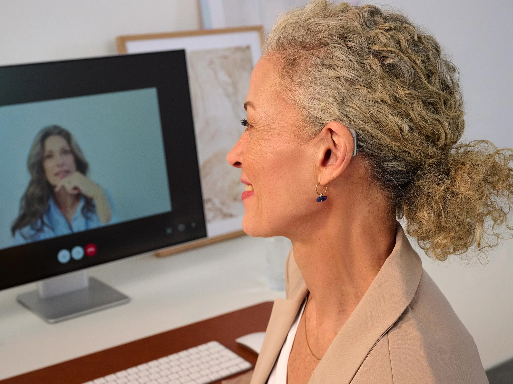 Woman working on a computer, wearing Widex Smart RIC hearing aids showing how small they are.