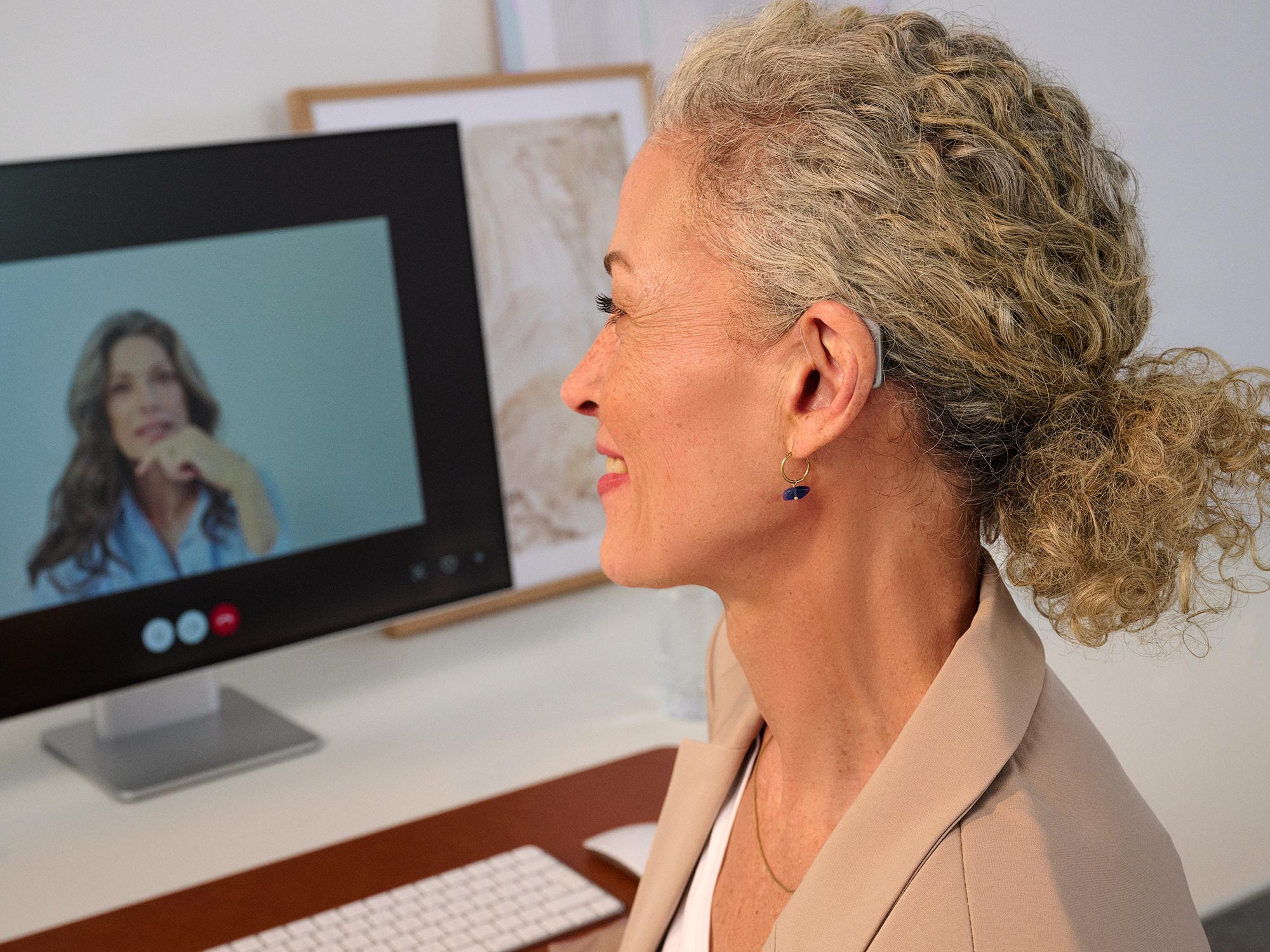 Woman working on a computer, wearing Widex Smart RIC hearing aids showing how small they are.