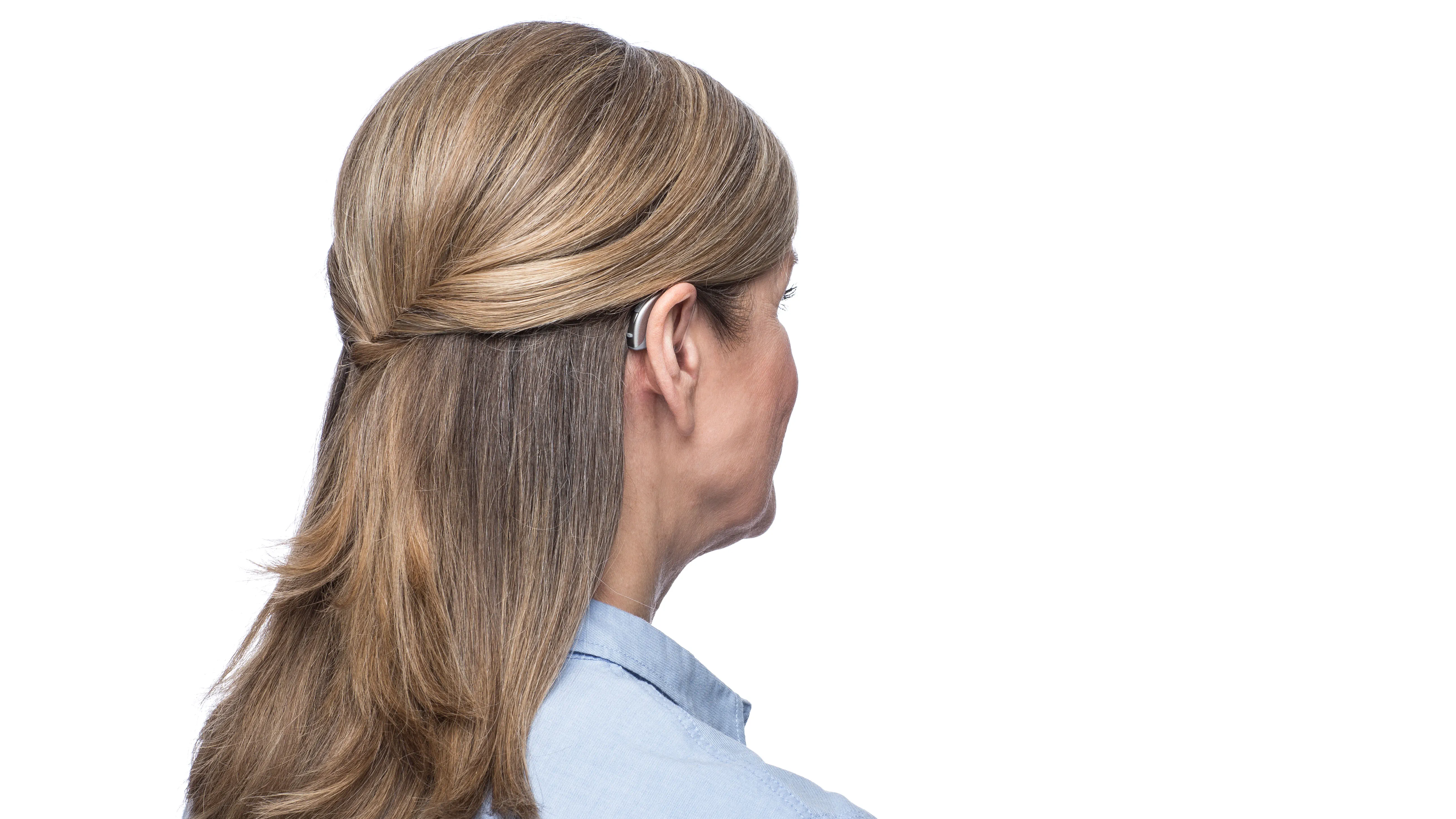 Woman wearing behind the ear hearing aid seen from side.