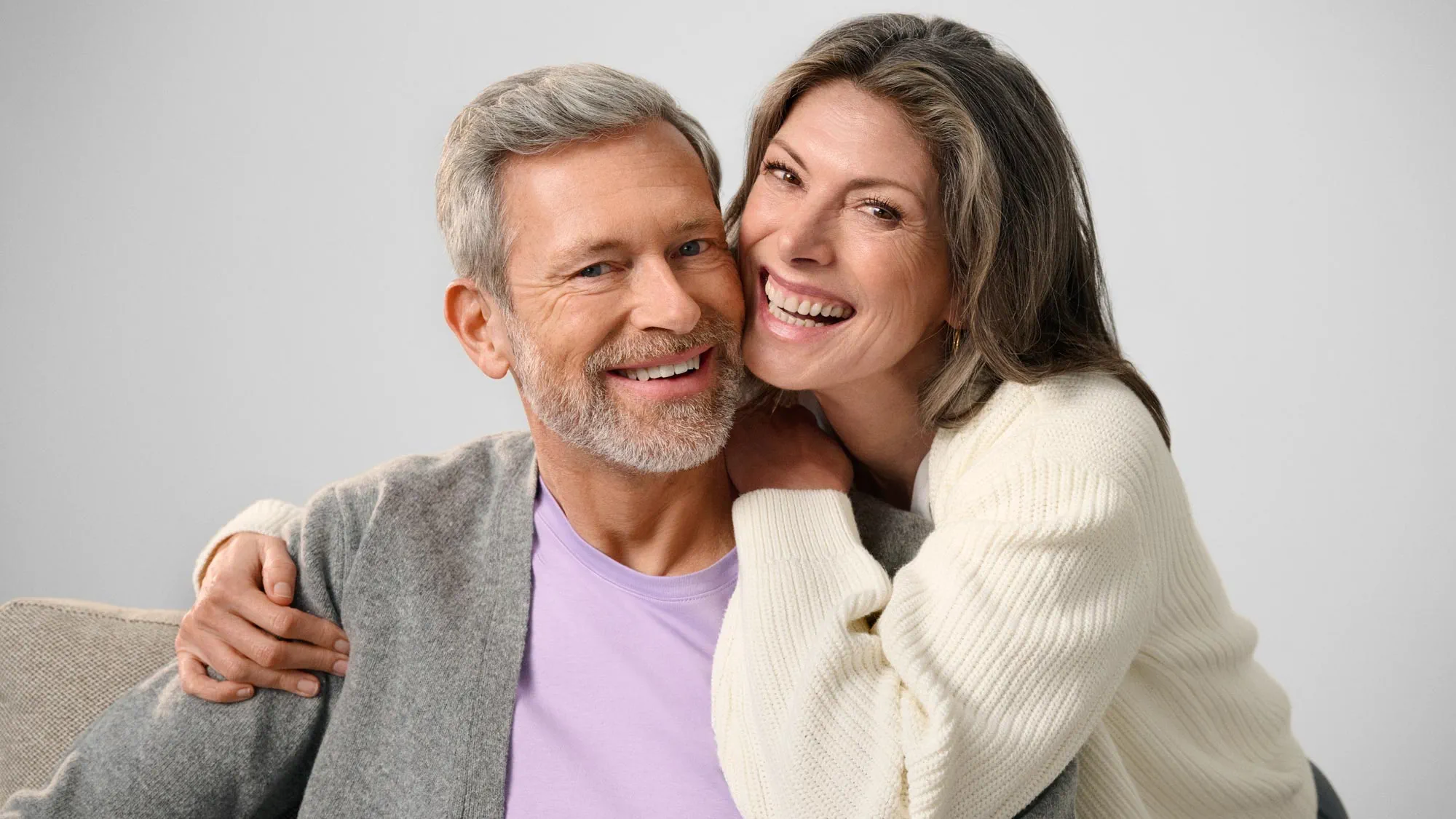 Casal a sorrir e a olhar um para o outro, mostrando melhoria auditiva.