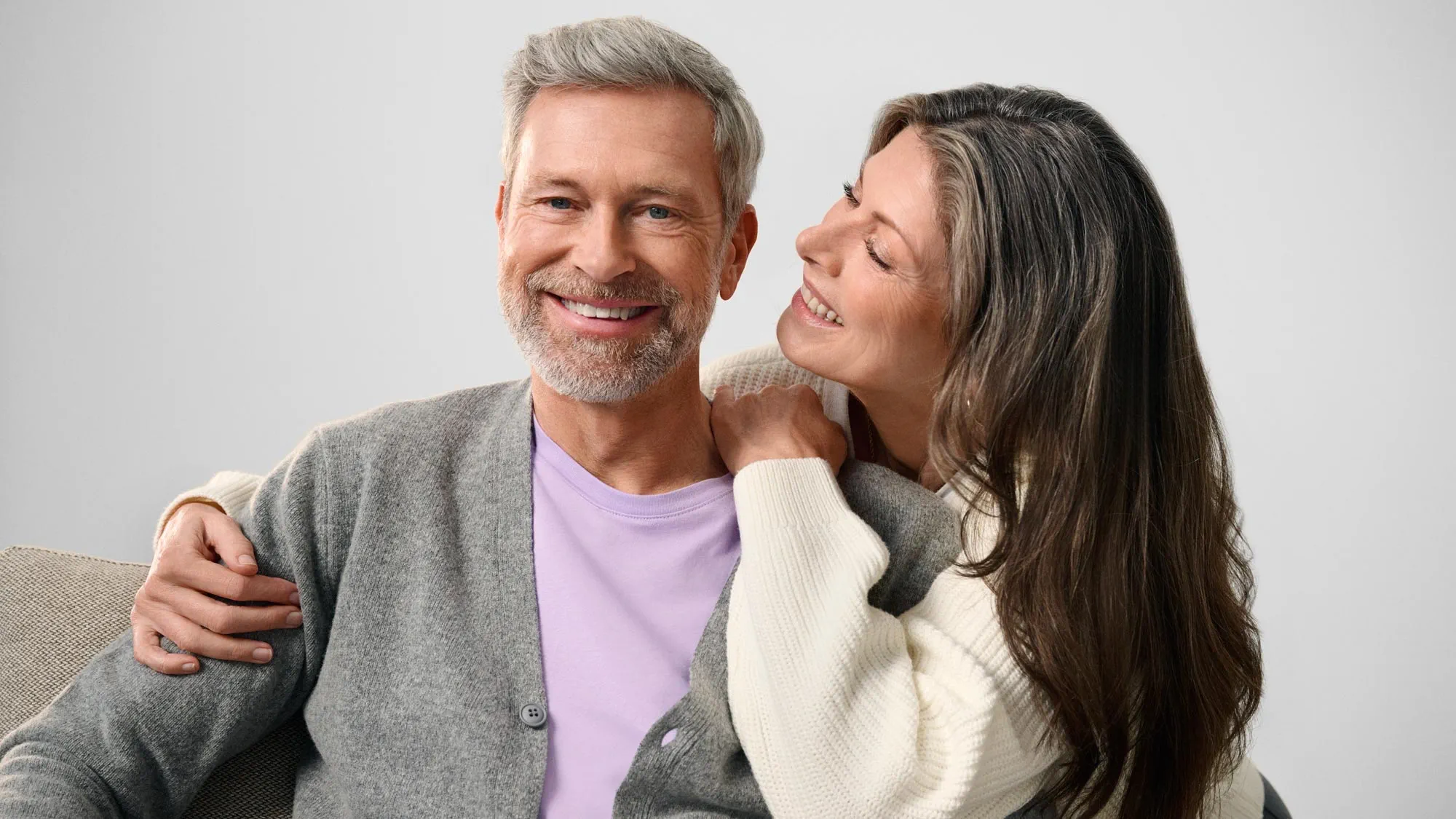 Homem feliz com o parceiro, indicando melhoria auditiva.