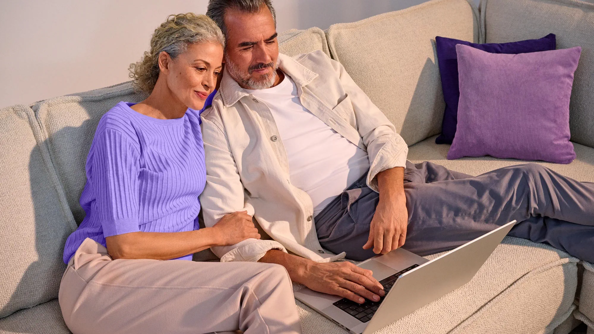 A couple looking comfortable, using technology with their hearing aids.