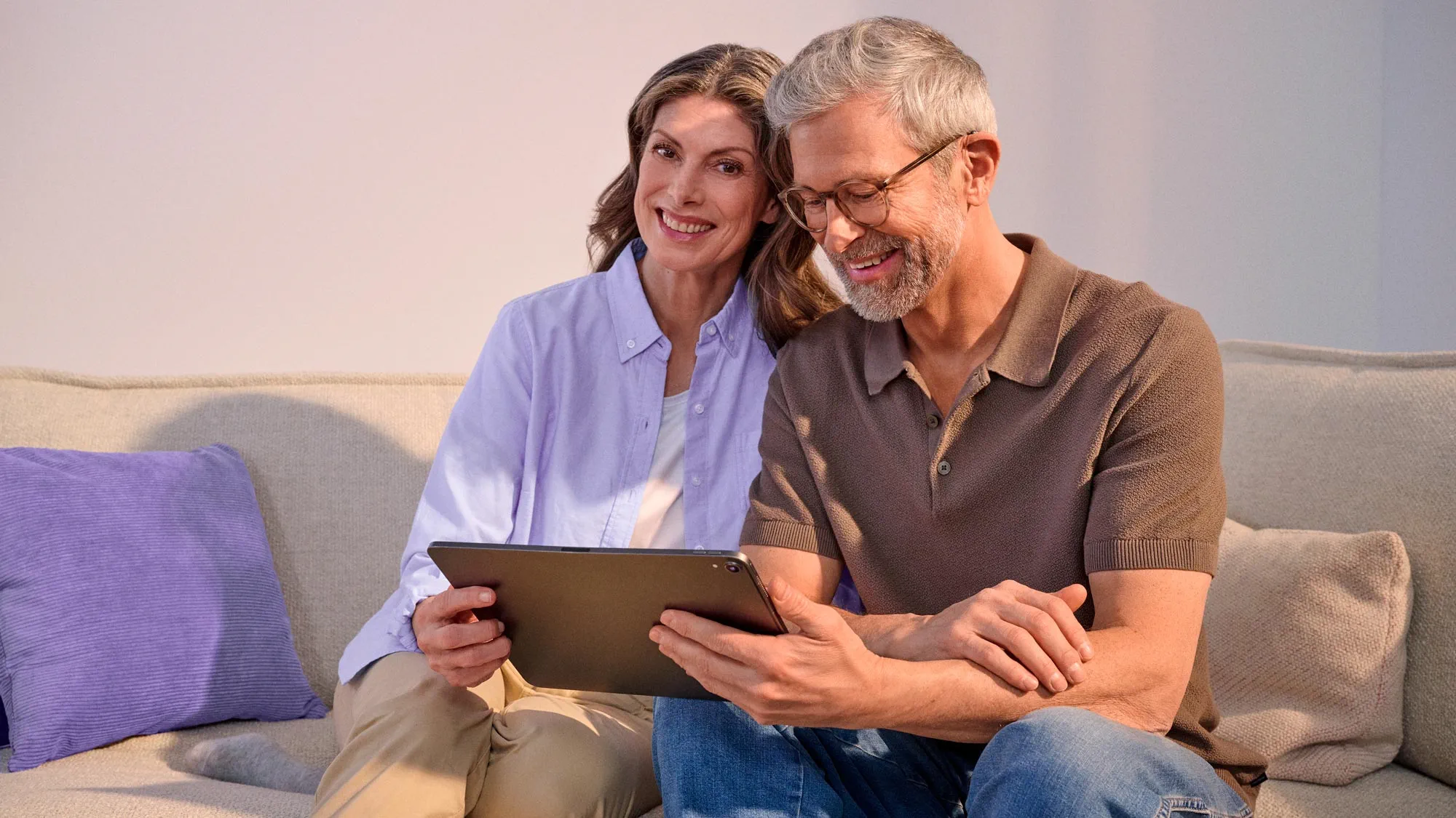 Casal a sorrir com tecnologia, ambos a usar aparelhos auditivos.