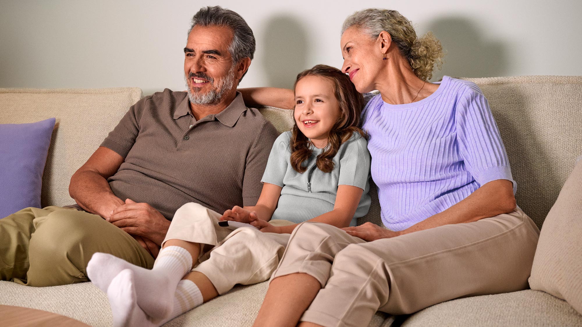 Grandparents casually watching TV, benefiting from hearing improvement.