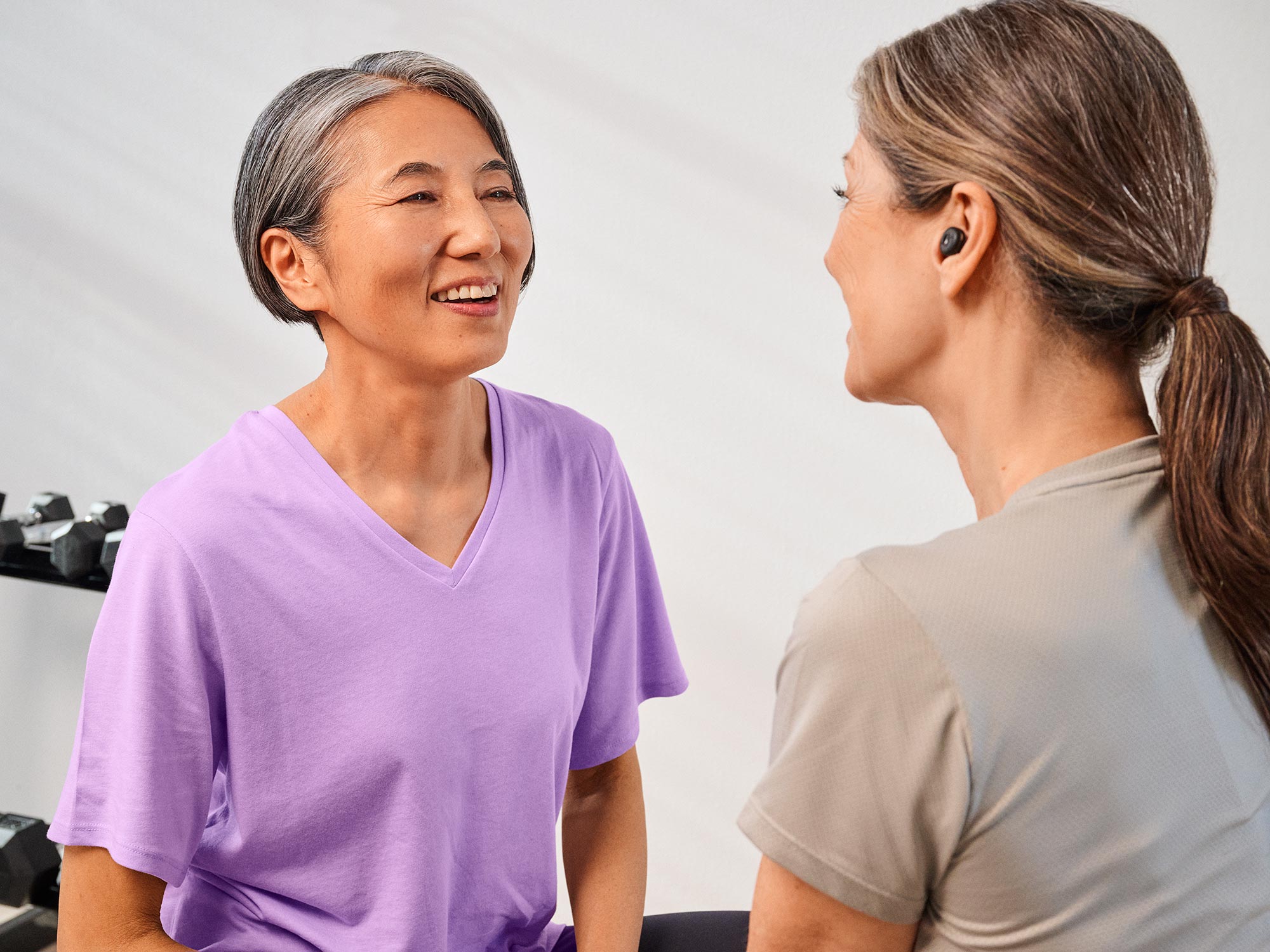 Friends talking at the gym, benefiting from their hearing improvement.