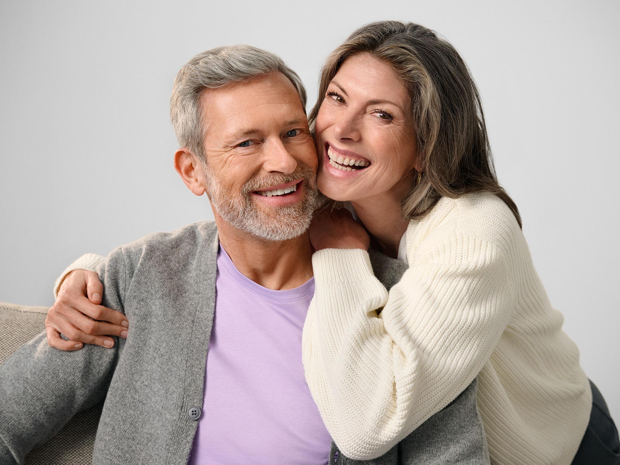 Couple laughing together, both wearing hearing aids.