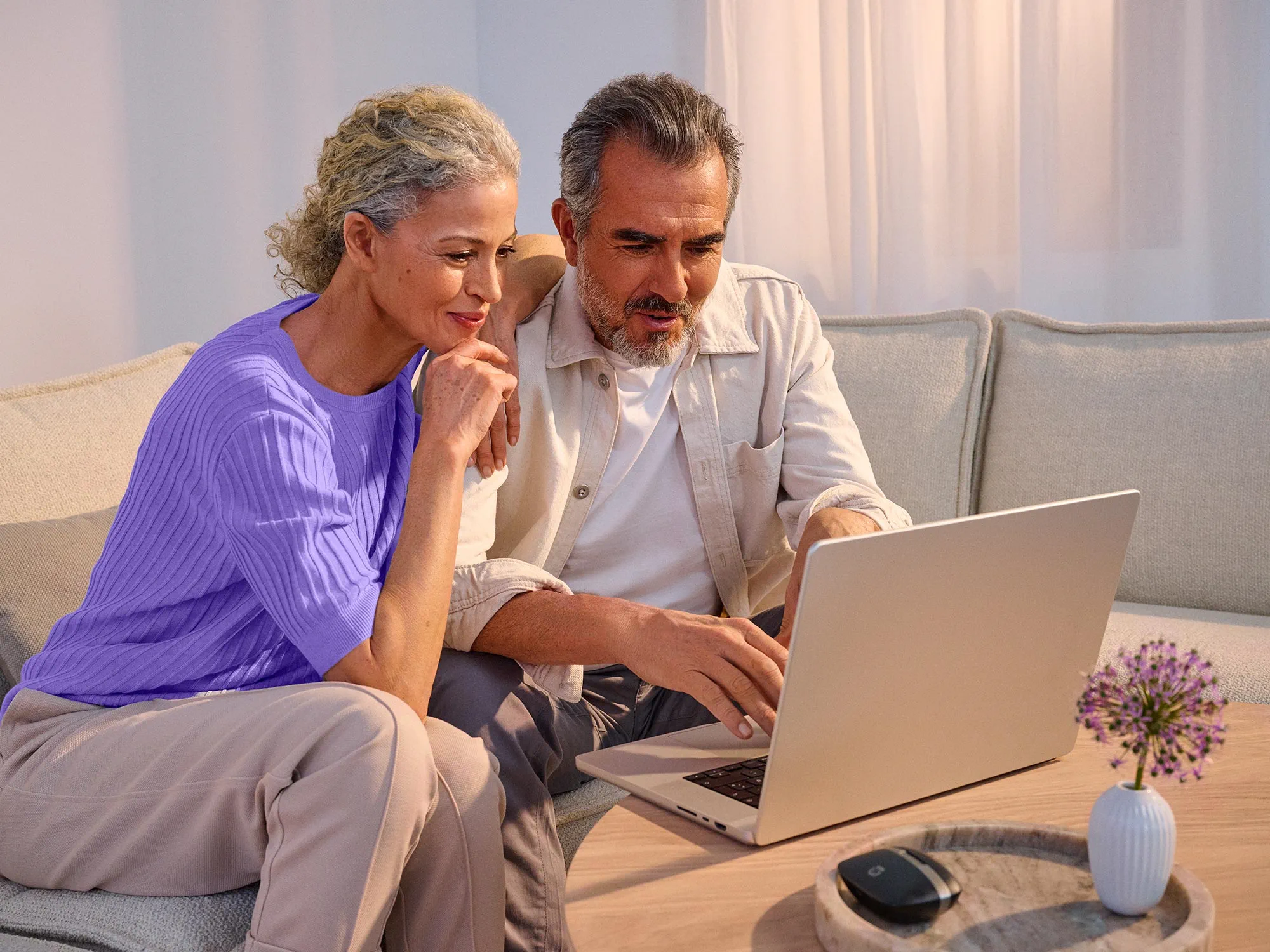 Casal a pesquisar tecnologia juntos, a usar os seus aparelhos auditivos.