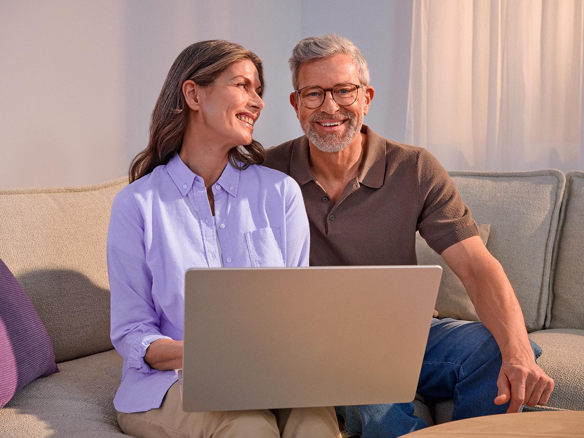 Happy couple using technology, both wearing hearing aids.