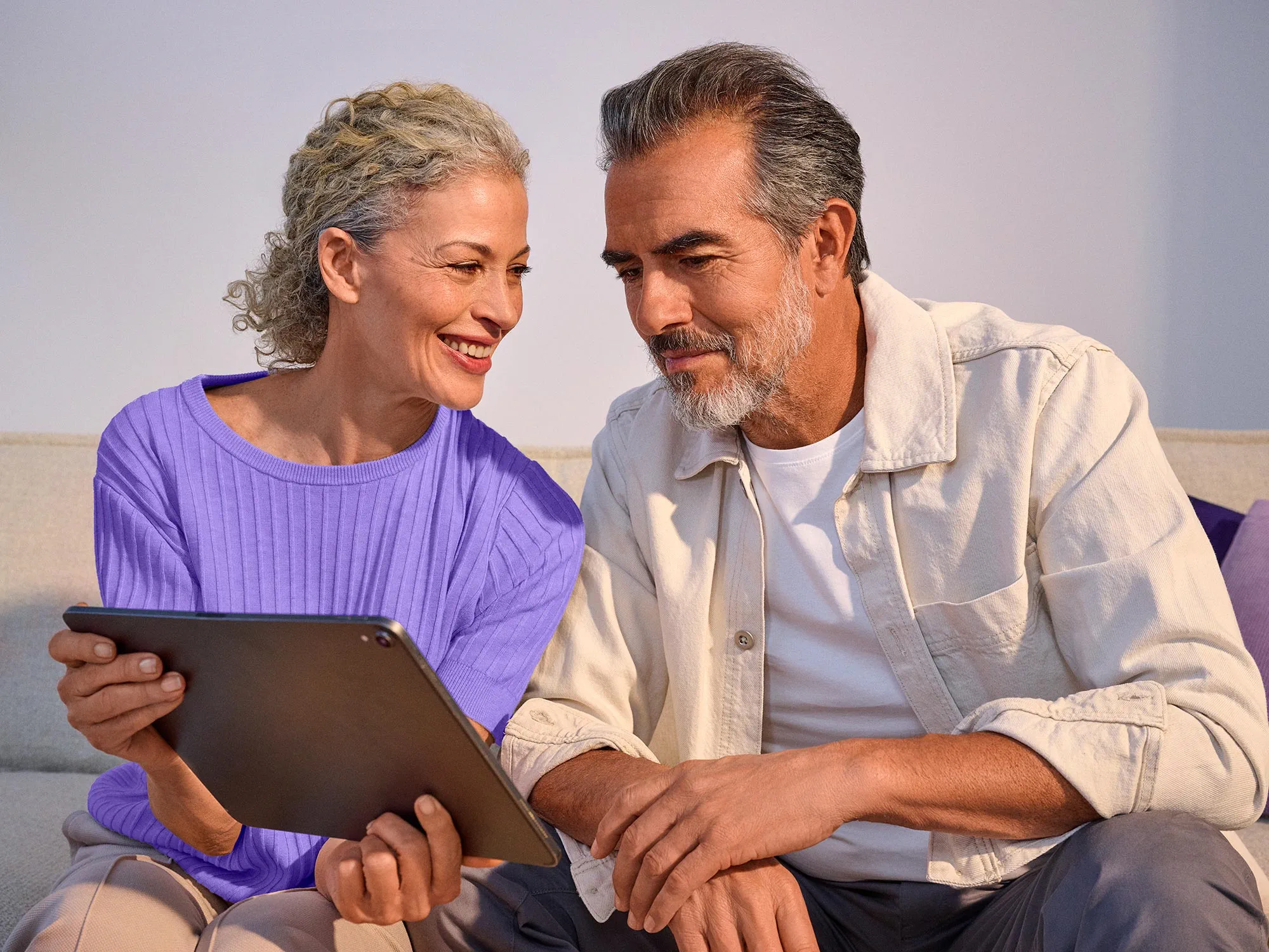 Couple showing each other something on technology, wearing hearing aids.