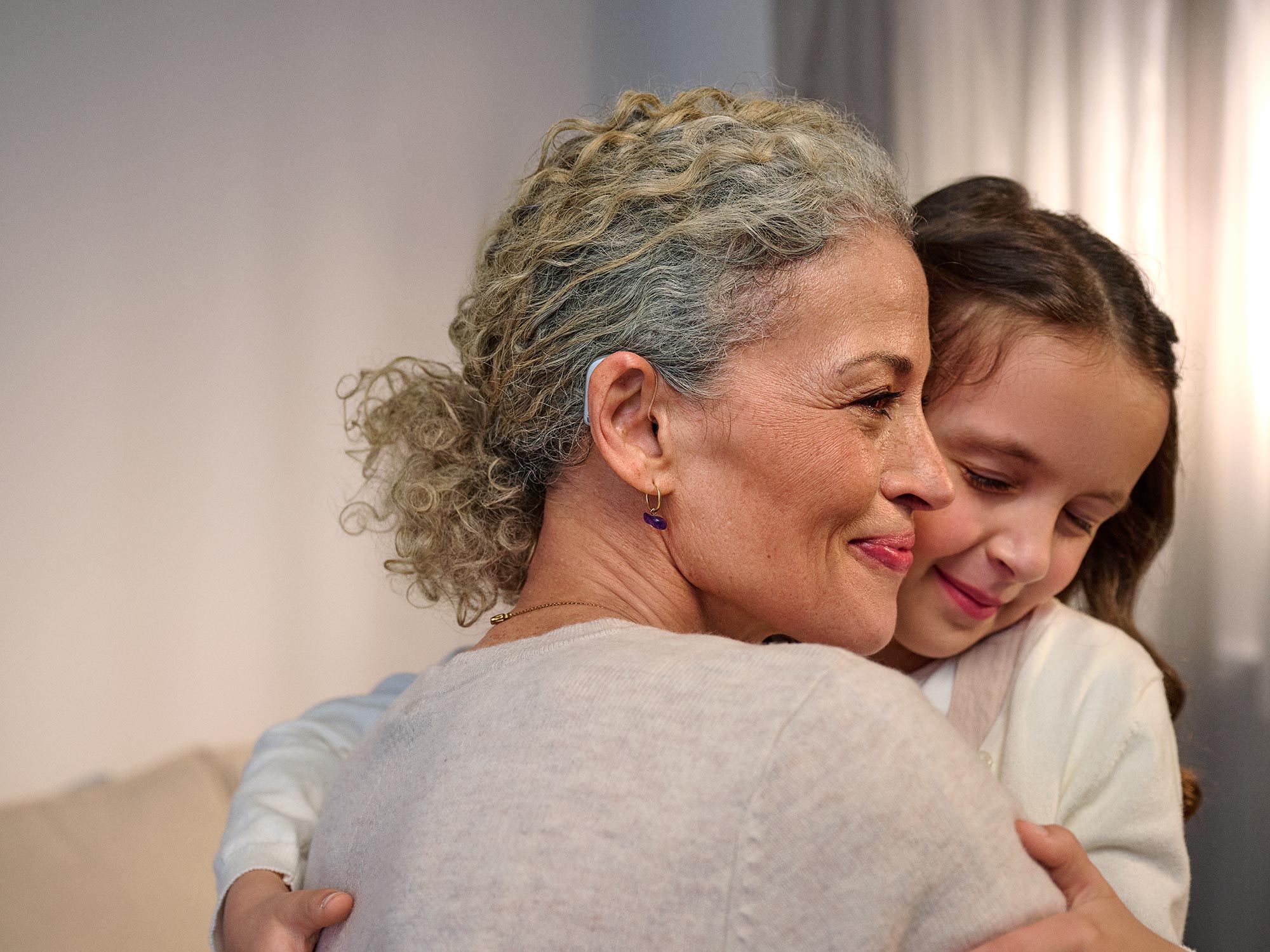 Grandmother embracing affectionately, enjoying hearing improvement.