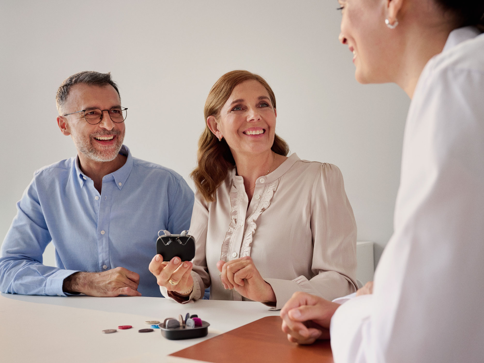 Hearing impaired customer choosing between hearing aids during an appointment with a specialist.