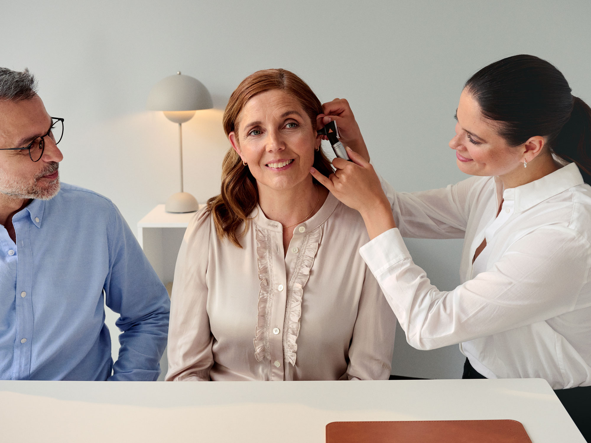 The audiologist performing an otoscopy on one ear of the customer during a hearing appointment.