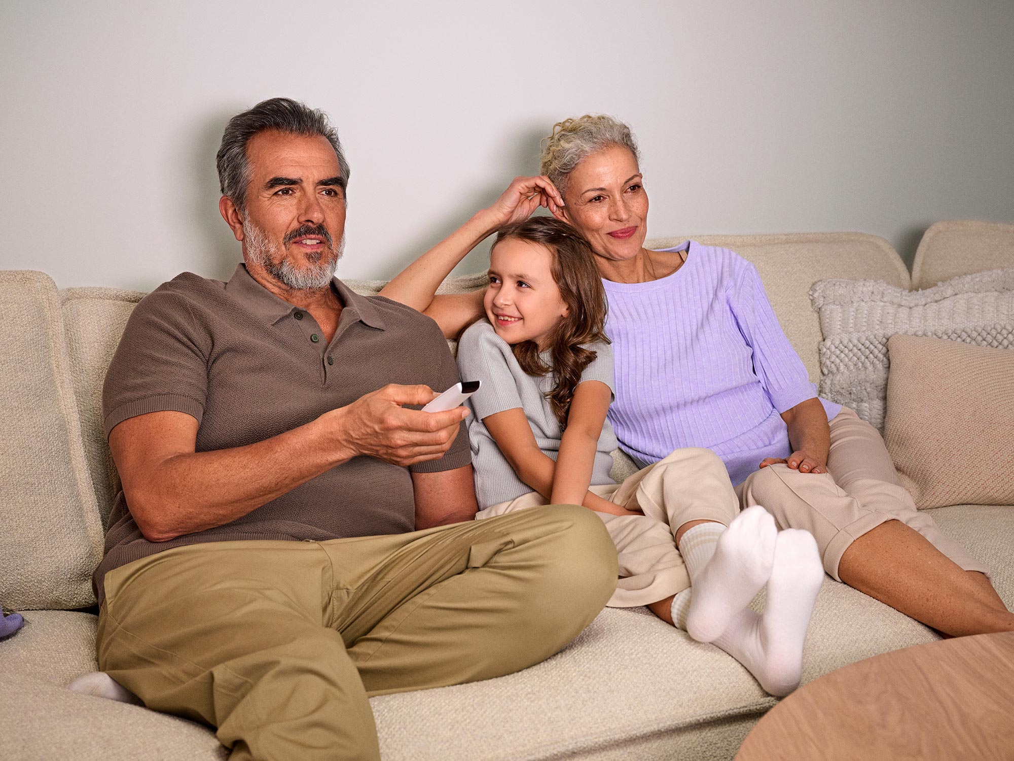 Avós a assistir televisão com entusiasmo, com aparelhos auditivos visíveis.
