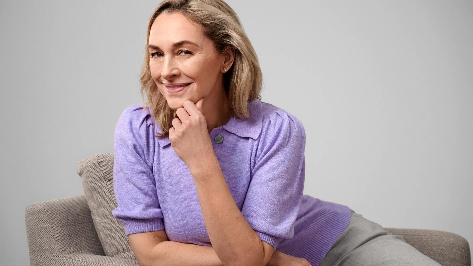 Content woman sitting comfortably, wearing hearing aids.