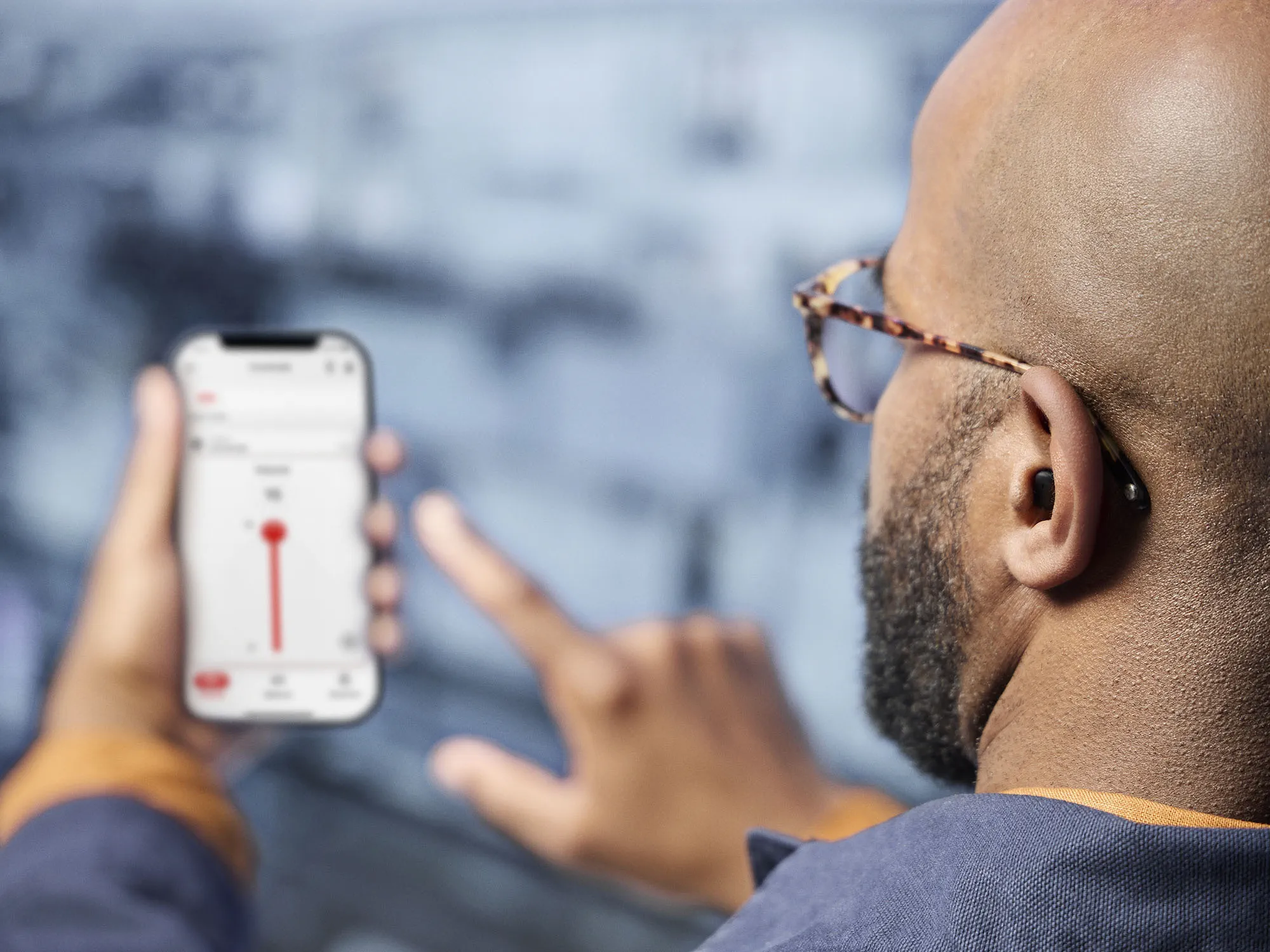 Man wearing Signia Insio Charge&Go CIC IX hearing aids whileadjusting sound from smart phone app