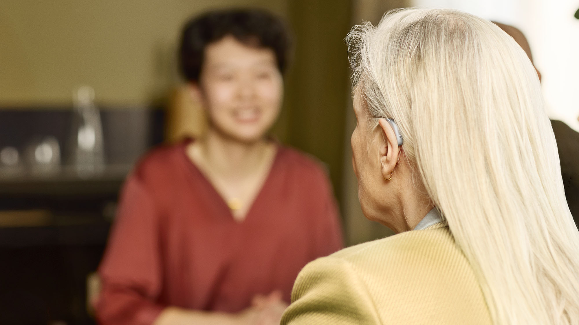 Signia Motion Charge&Go IX hearing aid worn behind ear enabling woman to participate in conversation.