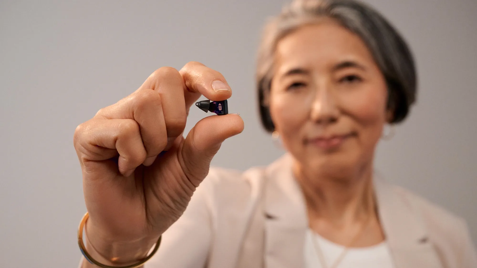 Woman holding Signia Silk between her fingers to show how tiny it is