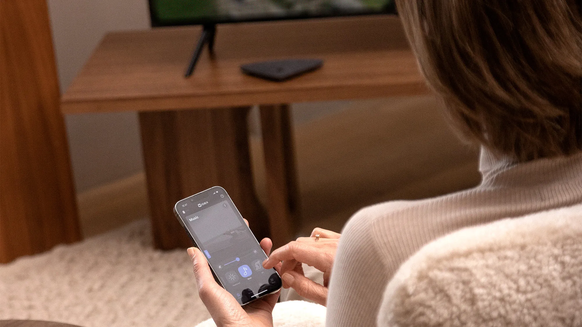Widex Moment Sheer 補聴器を装着した女性が、Widex TV Play に接続して補聴器に直接音を届けています。