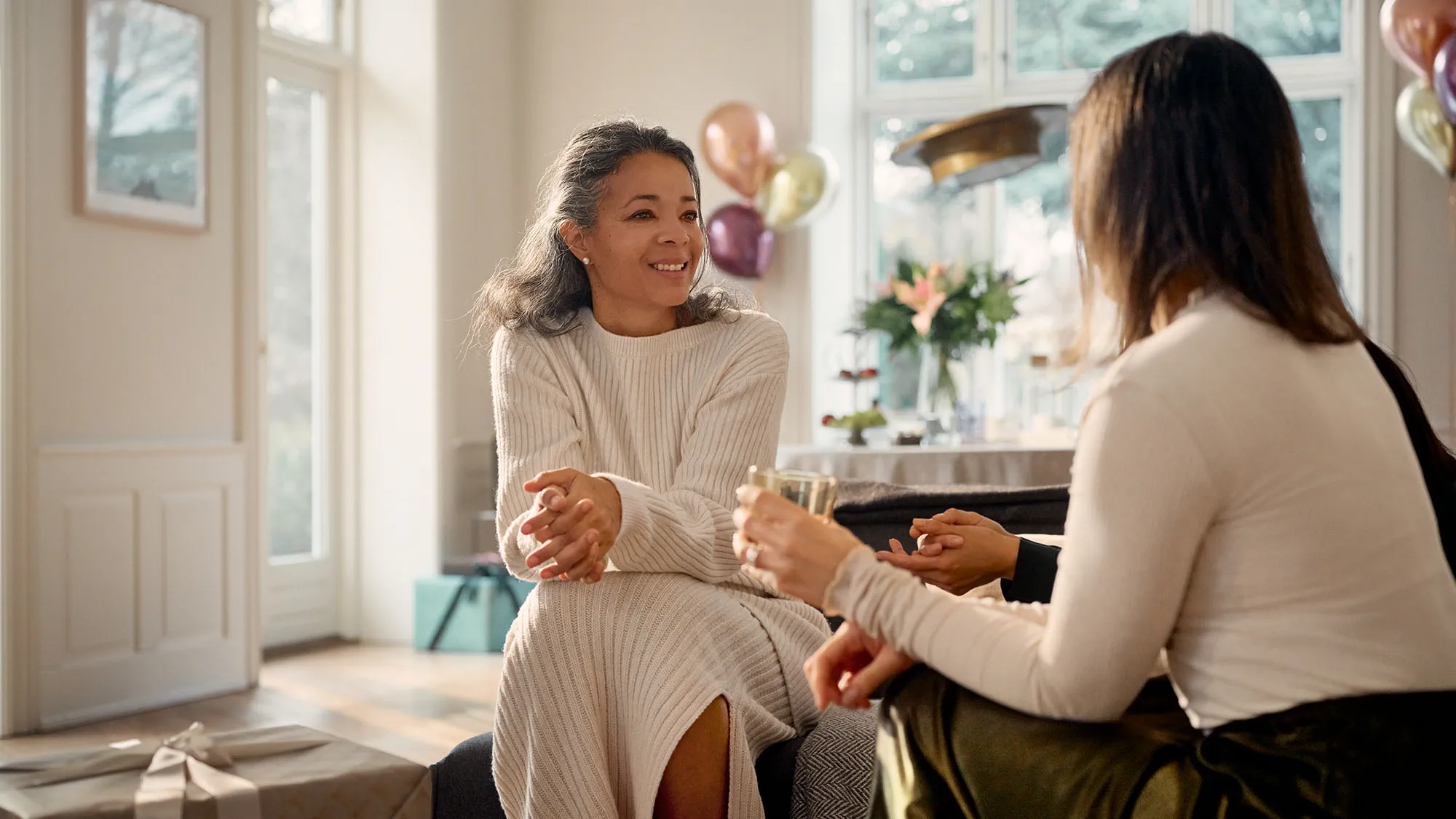 Woman wearing Widex Allure nearly invisible hearing aids while talking to friends being able to hear it all.