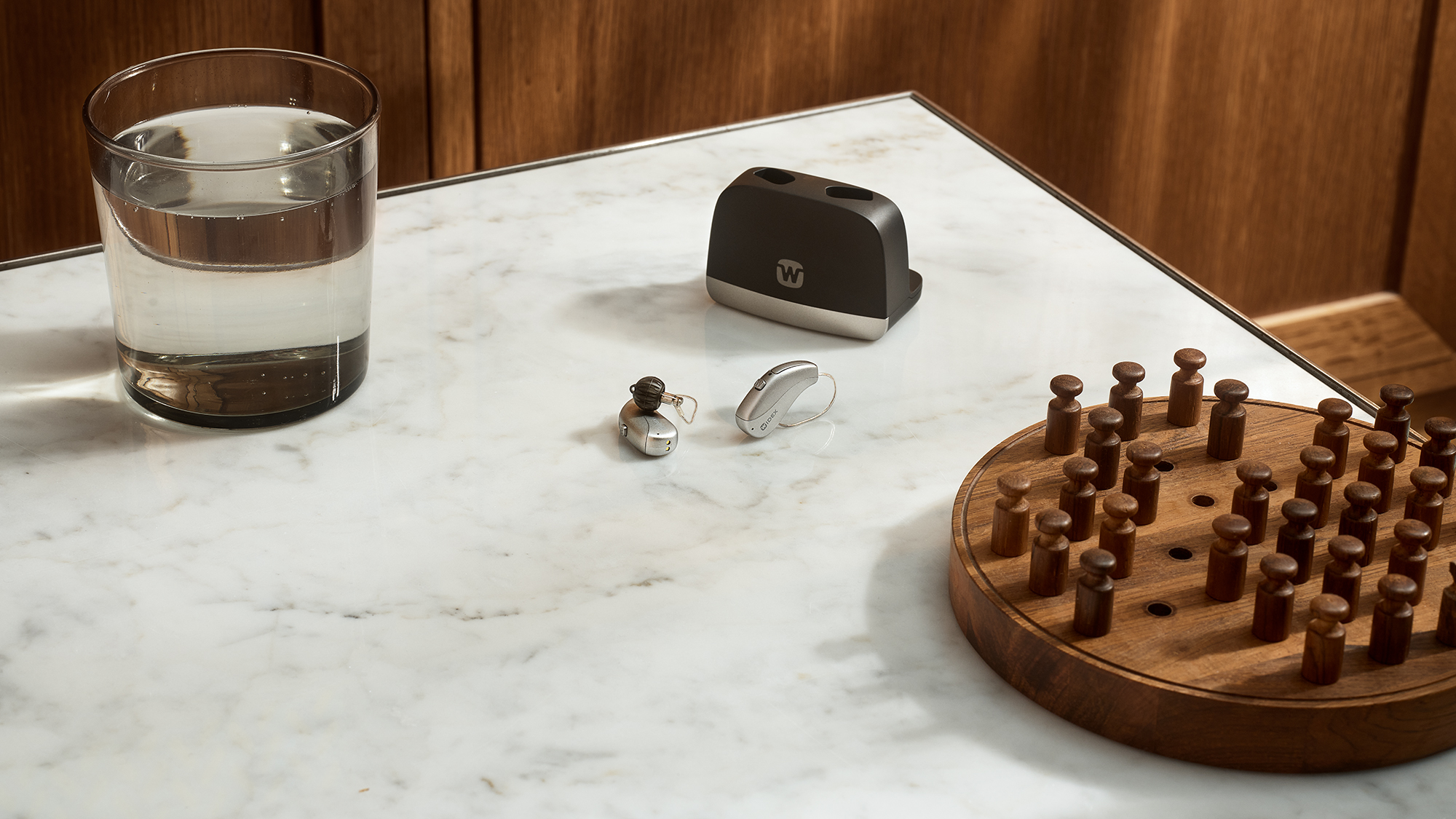Widex Allure hearing aids shown next to glass to illustrate how small they are.