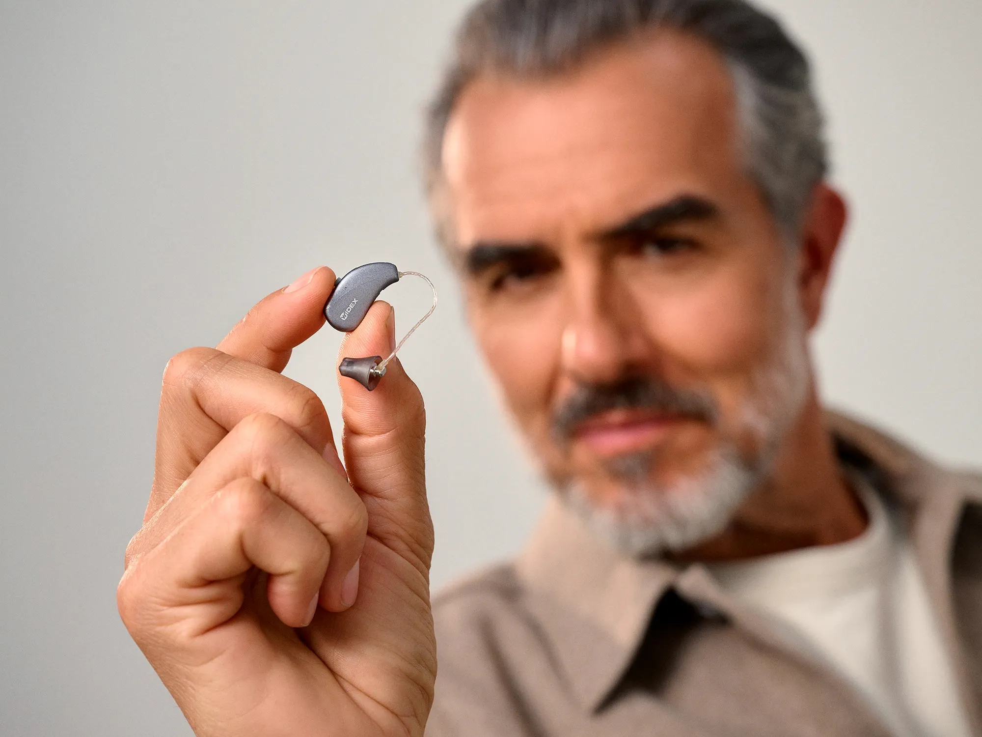 man-pinching-widex-moment-sheer-s-ric-hearing-aid-4x3