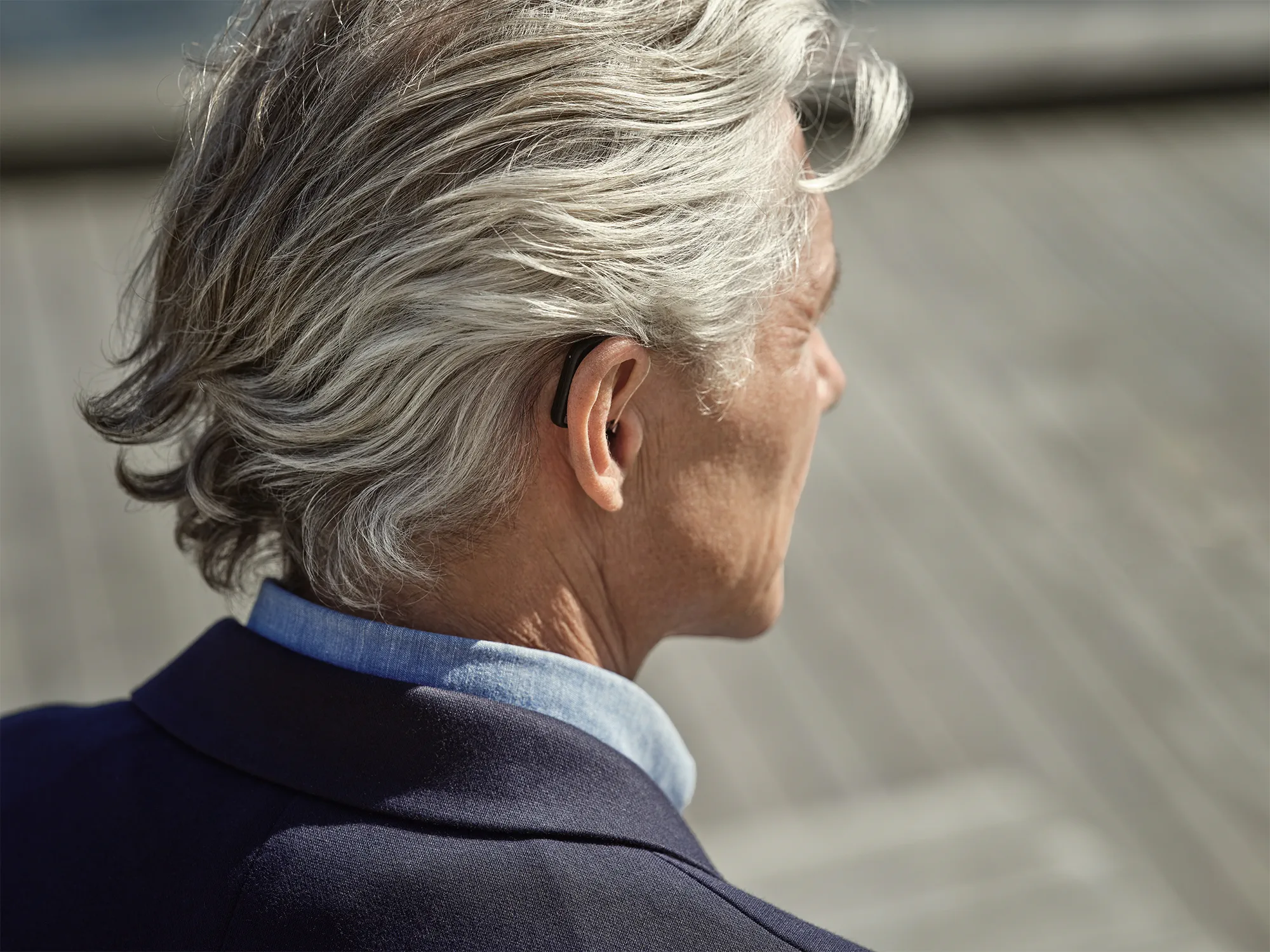 Man wearing Widex SmartRIC hearing aids behind the ear hearing conversations in the street.
