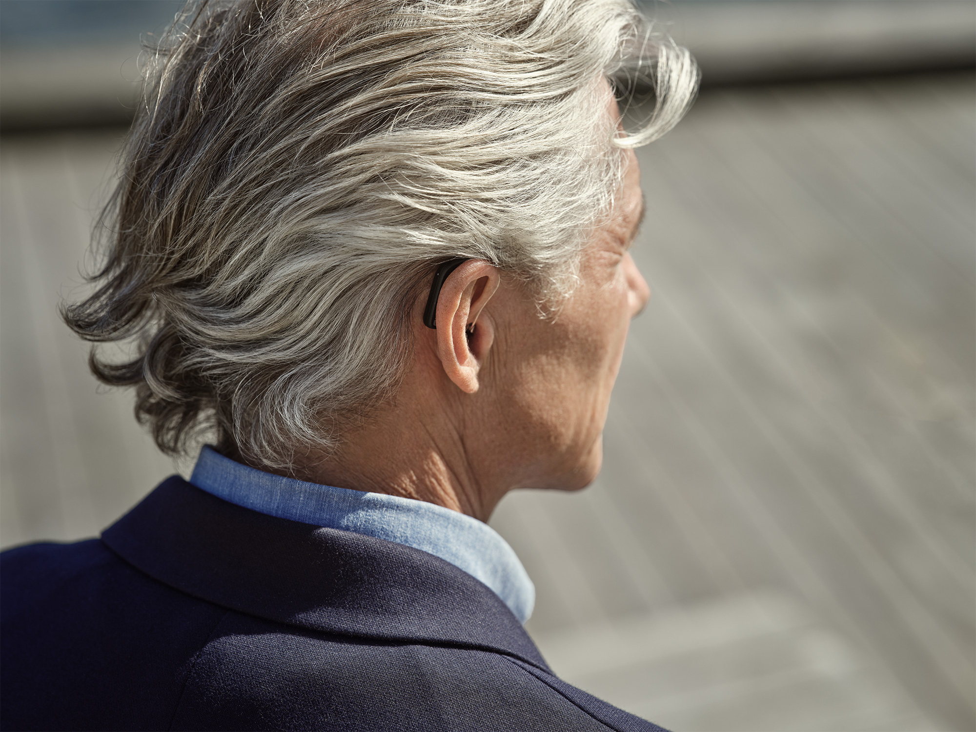 Man wearing Widex SmartRIC hearing aids behind the ear hearing conversations in the street.