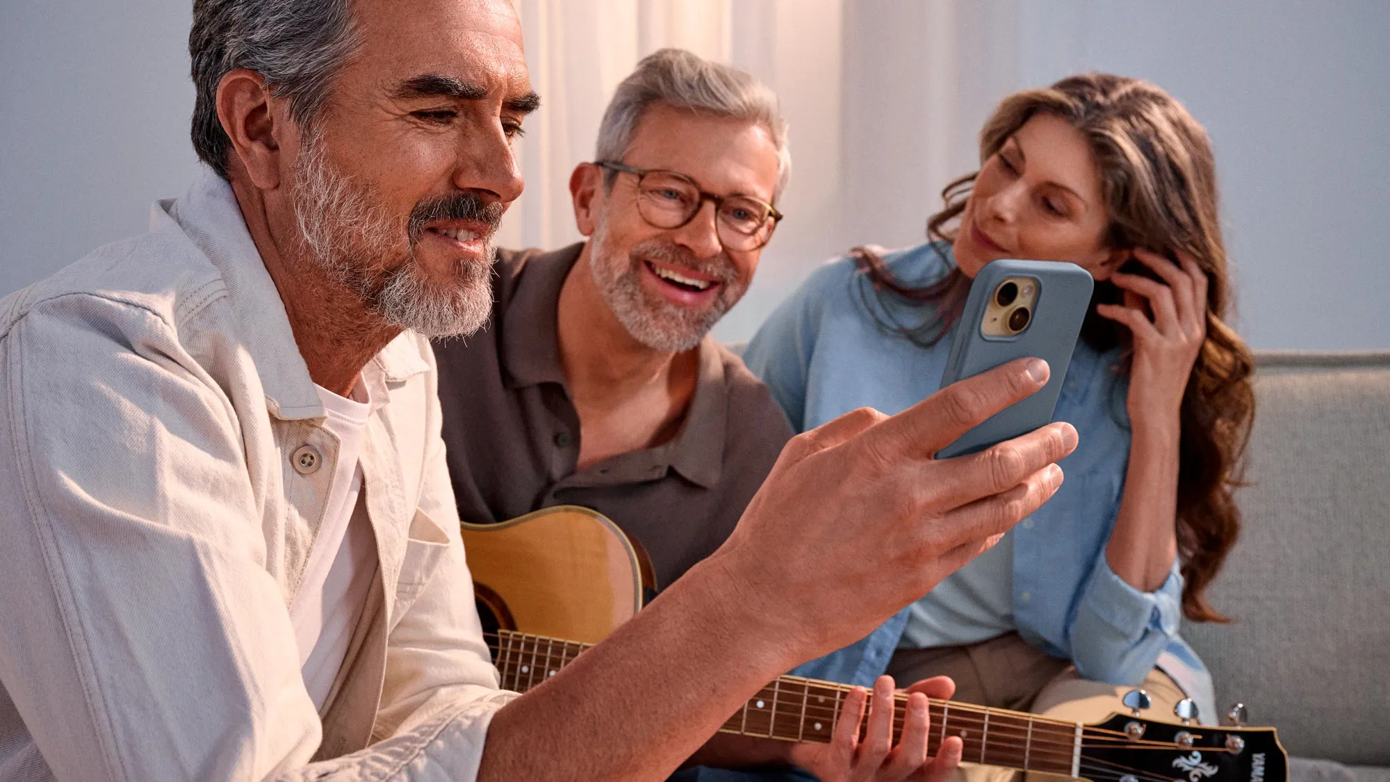 Casual group of friends looking at a phone, celebrating their hearing improvement.