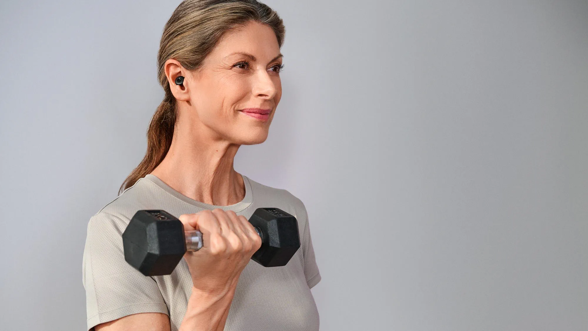 Empowered woman at the gym, wearing hearing aids.