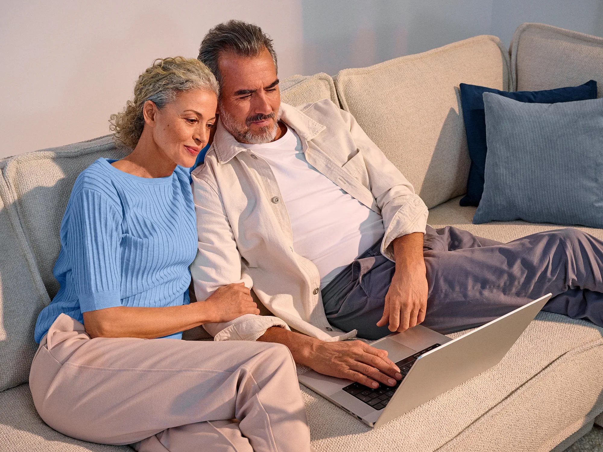A couple looking comfortable, using technology with their hearing aids.