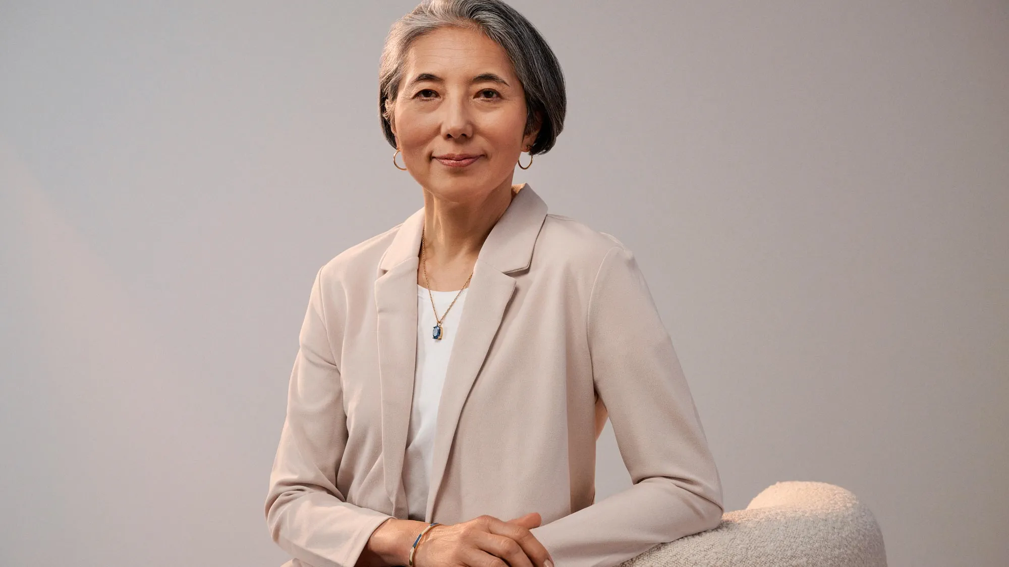 Confident woman sitting, wearing hearing aids.