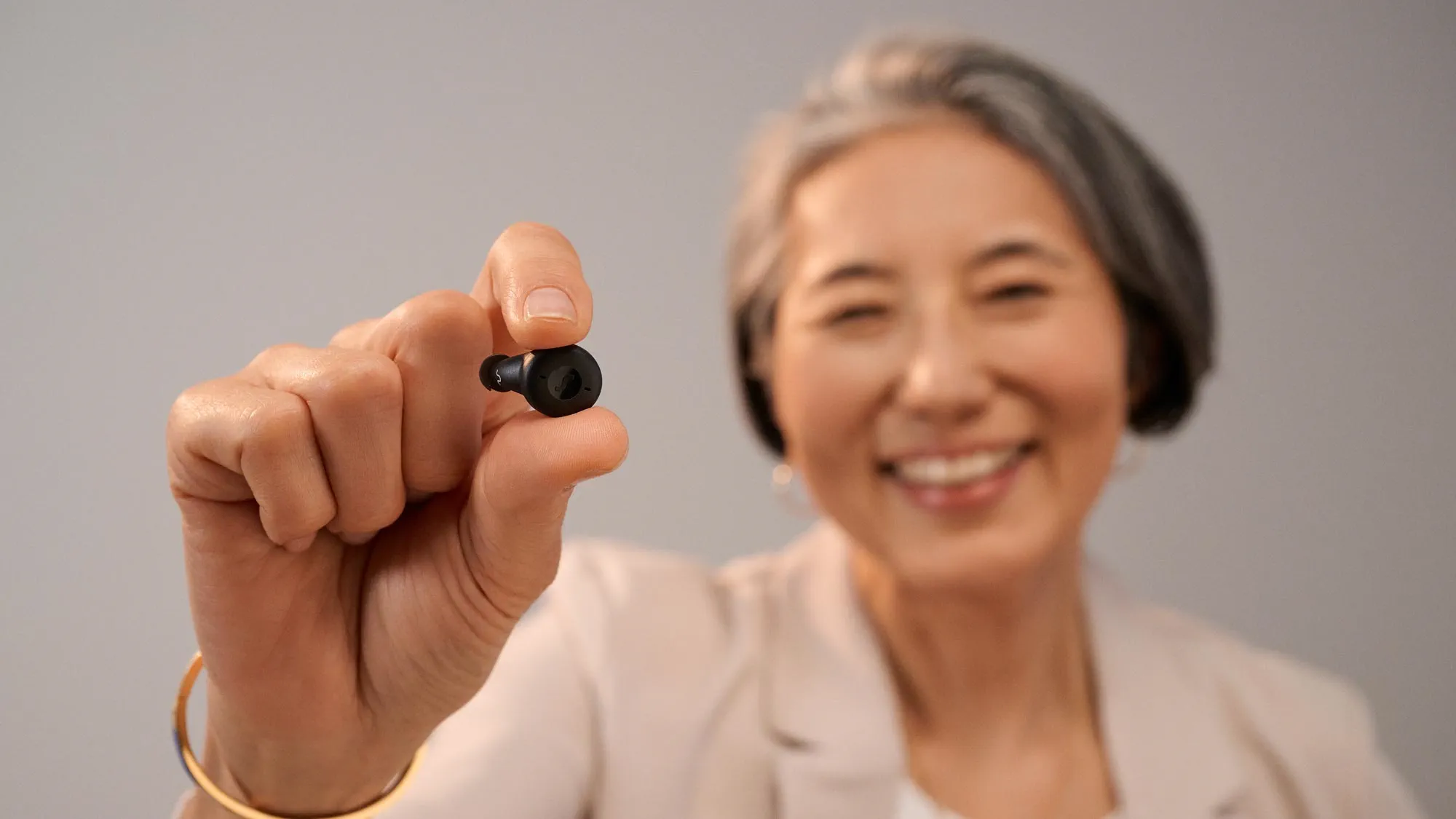 Woman holding Signia Active between her fingers to show how tiny it is