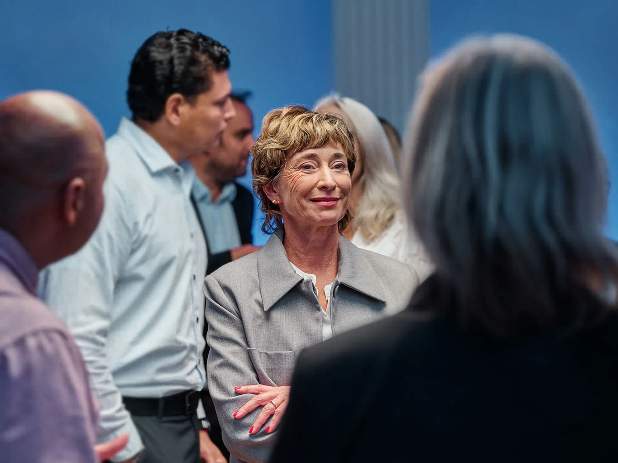 Group of people discussing hearing-loss solutions, with one person using hearing-aids to stay engaged and communicate effectively.