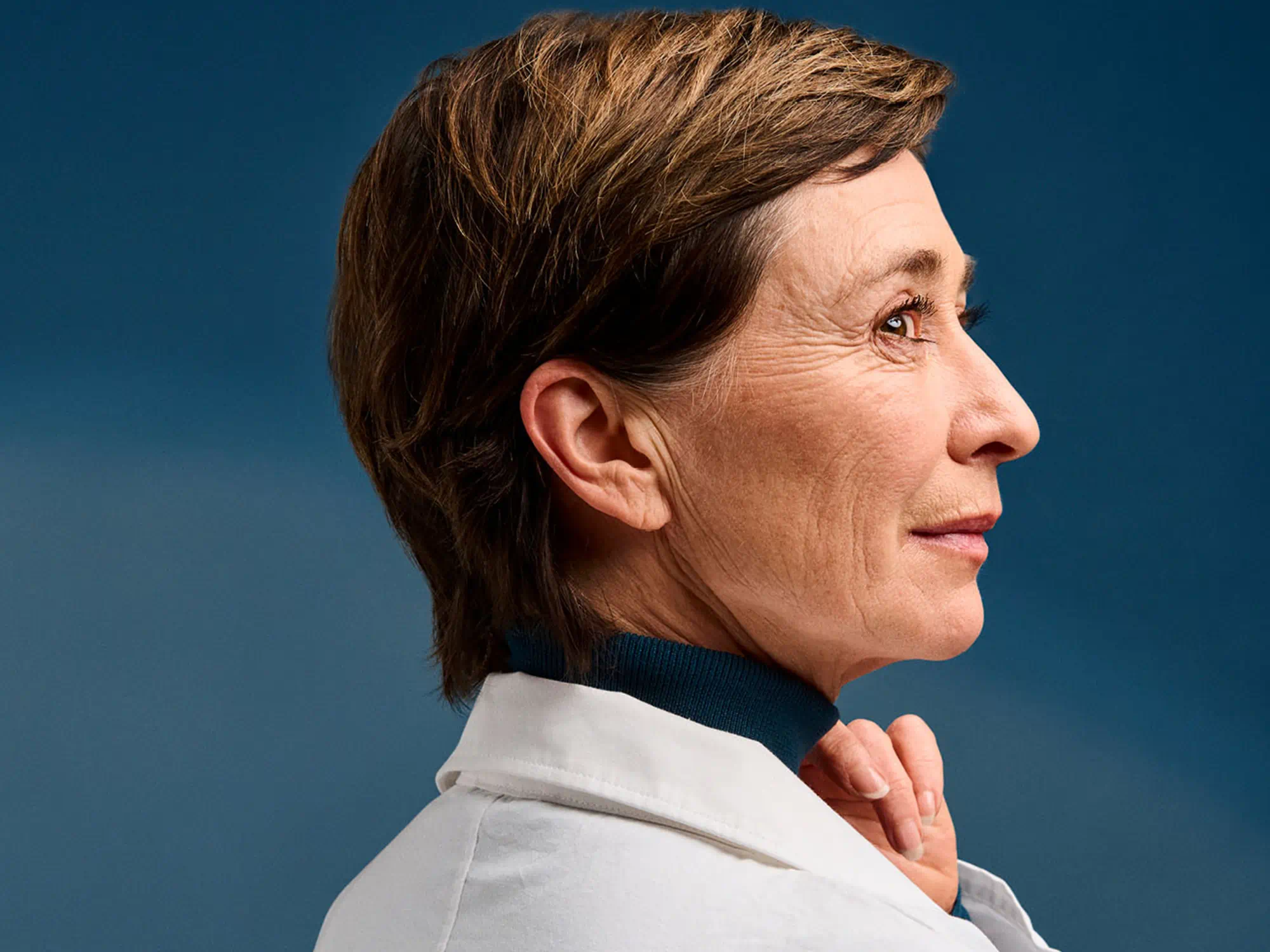 Professional with hearing-loss wearing hearing-aids, confidently presenting in a white coat against a blue background.