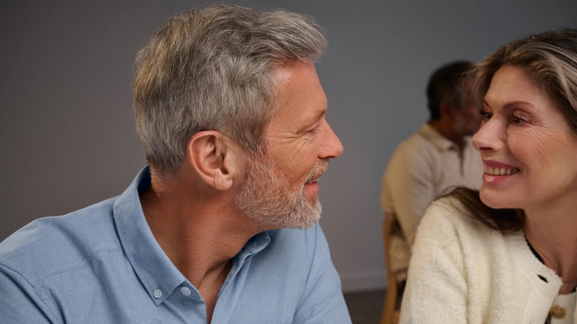 Couple talking while man is wearing Widex Moment RIC hearing aids.