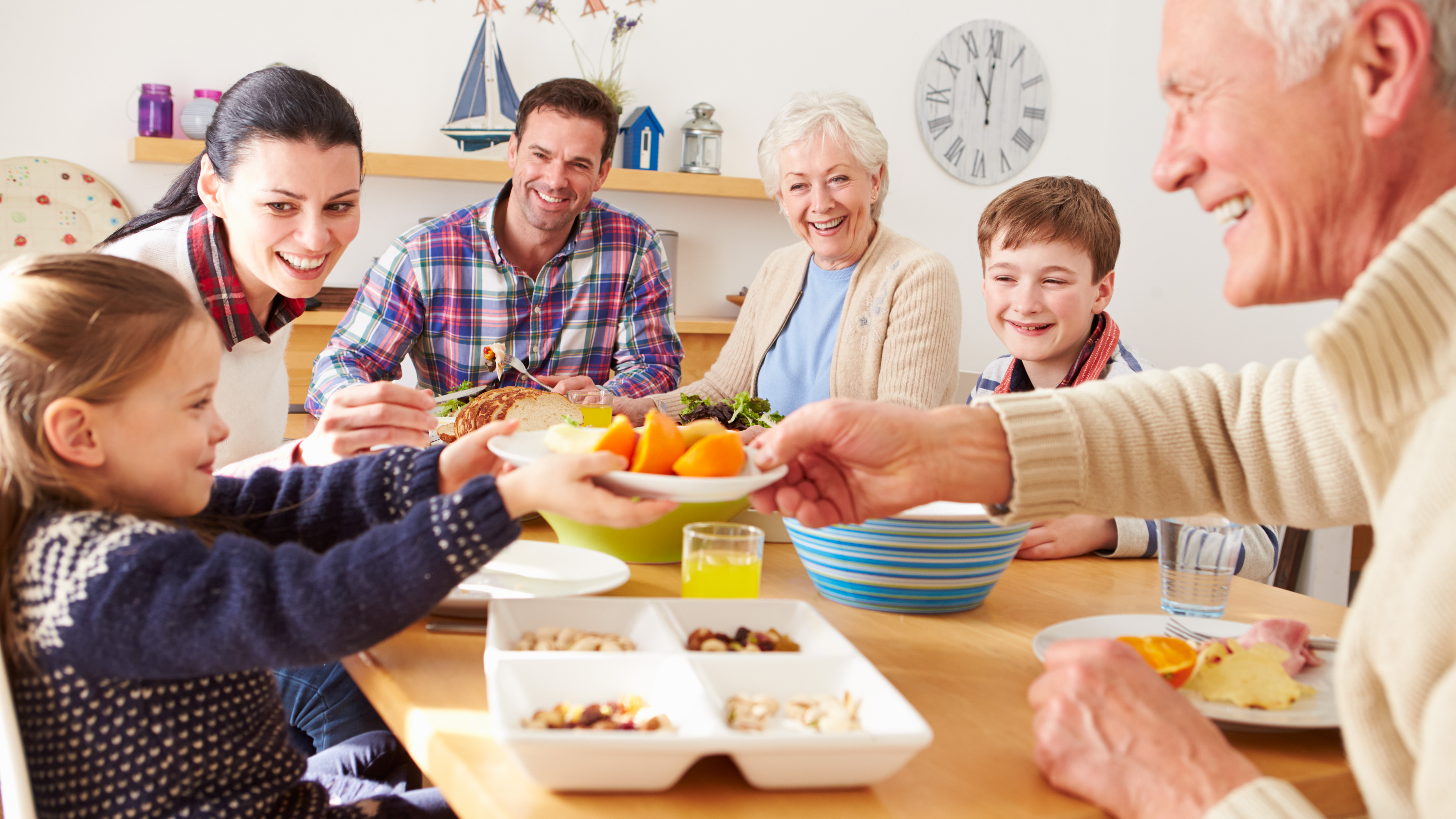 Multi generation family eating lunch at kitchen table using hearing aids