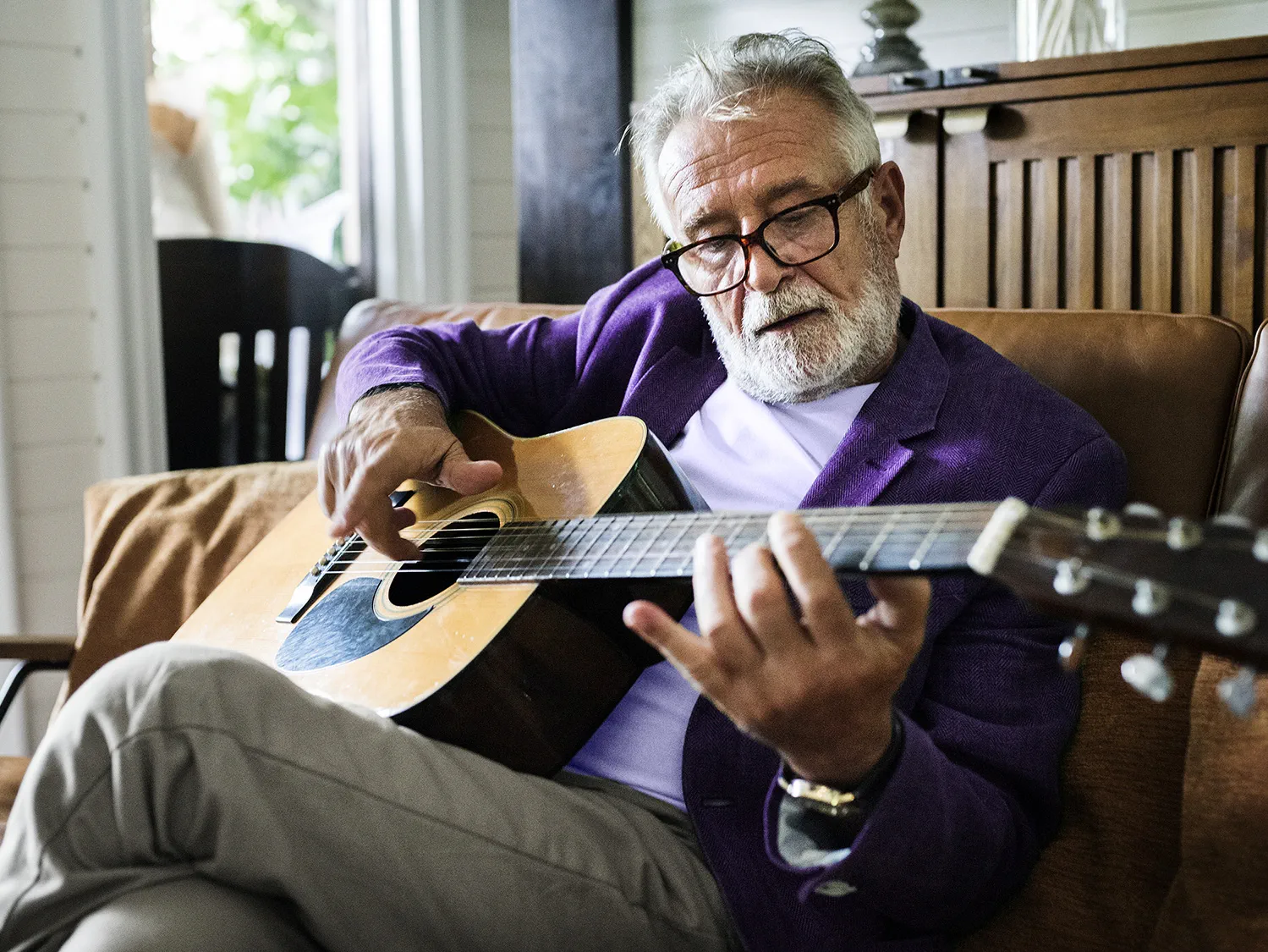 Ein älterer Mann mit Hörgerät spielt akustische Gitarre